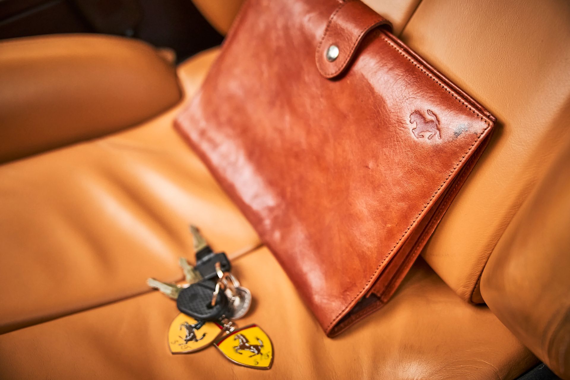 A wallet and keys are sitting on the back seat of a car.