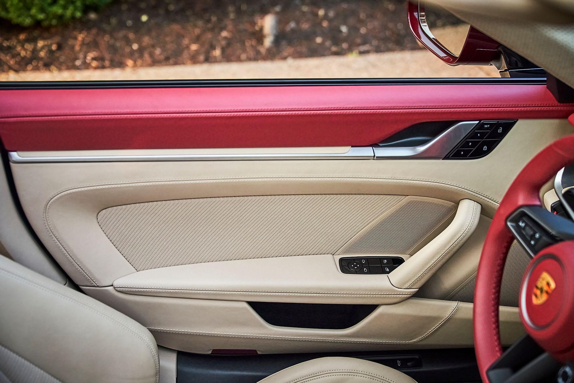The inside of a car with the door open and a red steering wheel