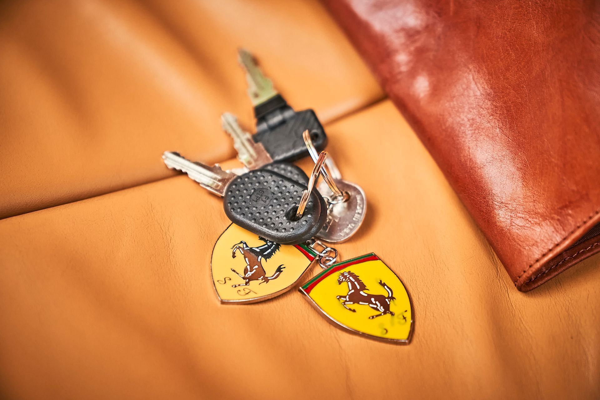 A bunch of keys are sitting on top of a brown leather wallet.