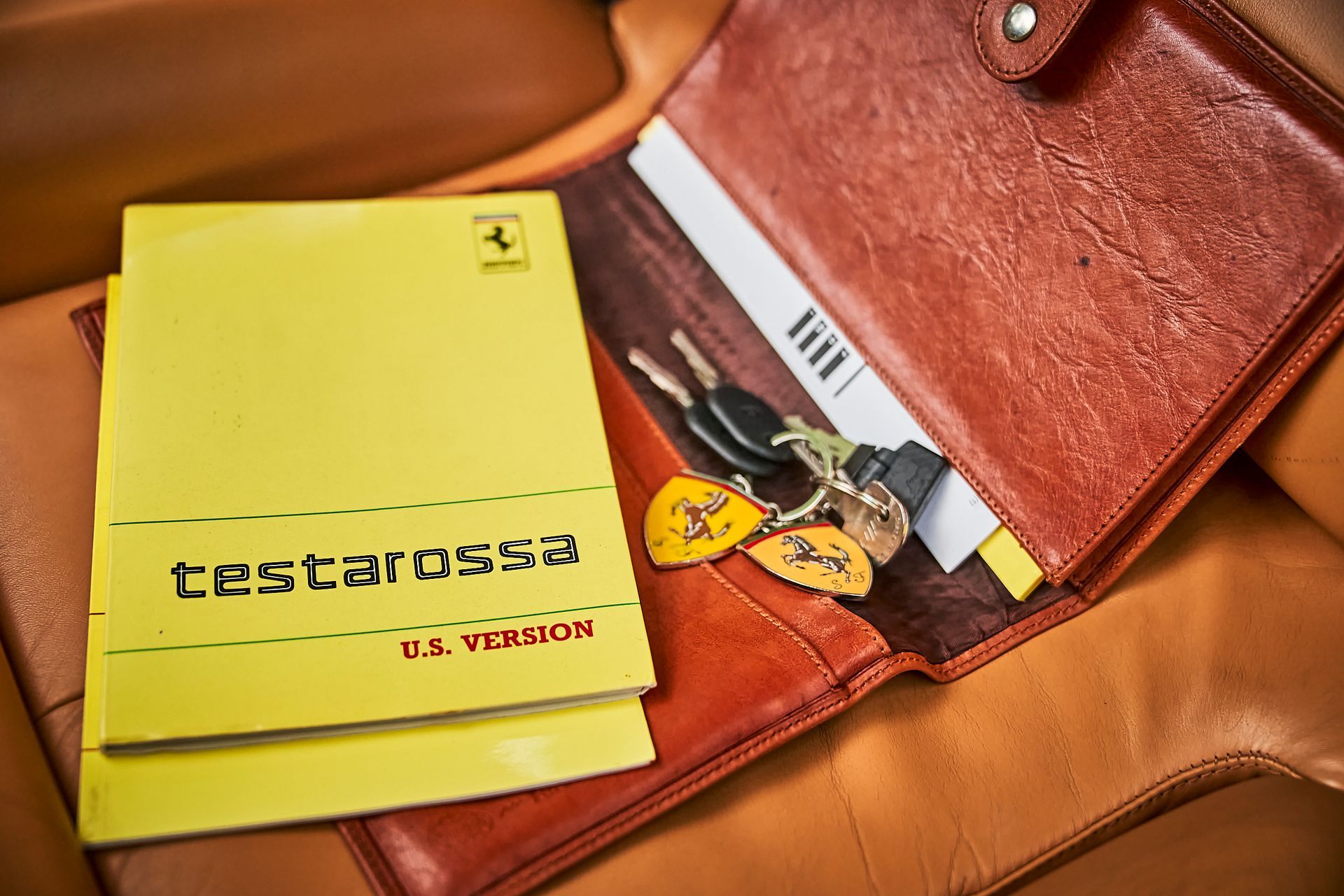 A close up of a wallet with a yellow book and keys in it.