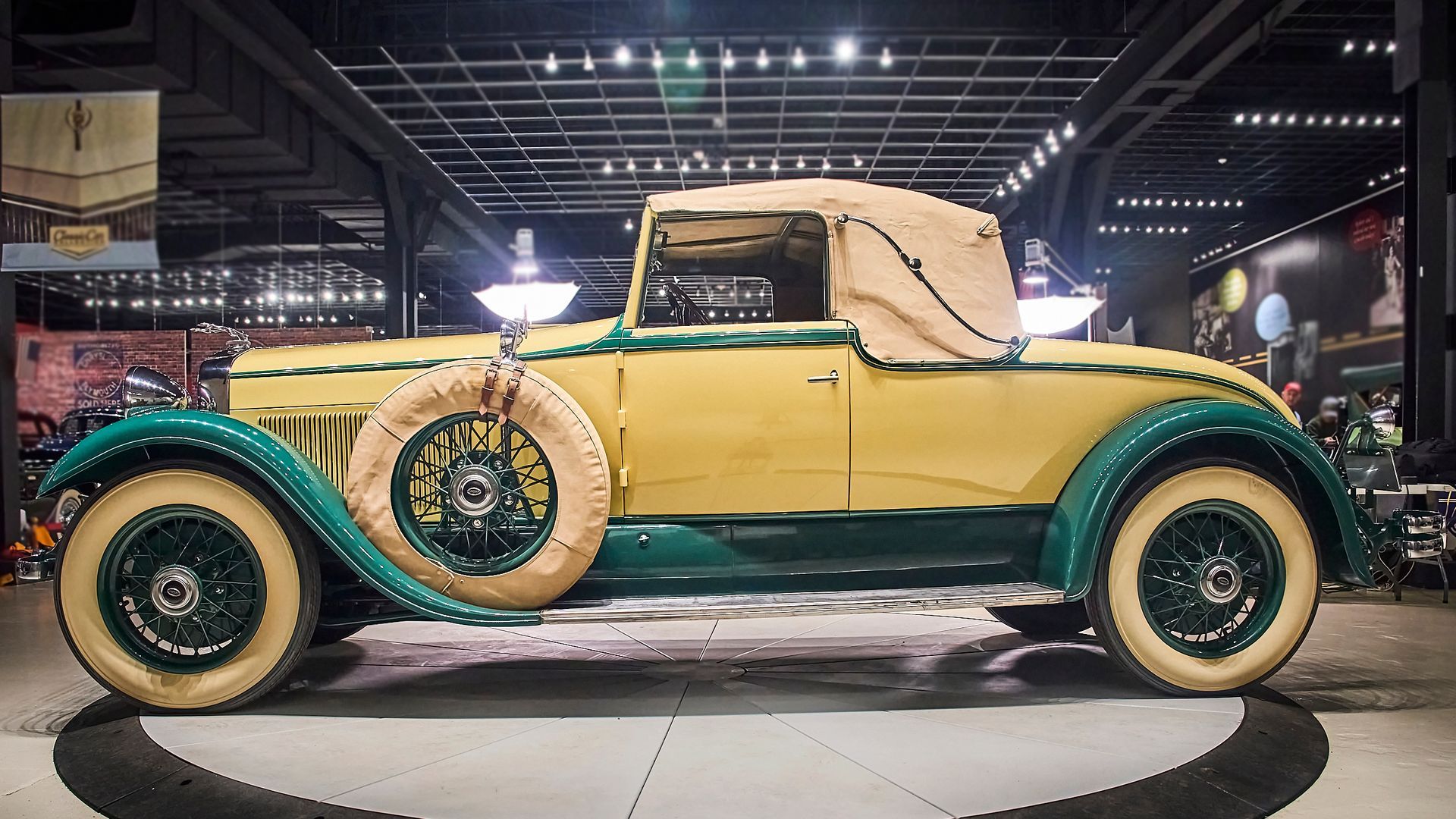 A yellow and green vintage car is parked in a garage.
