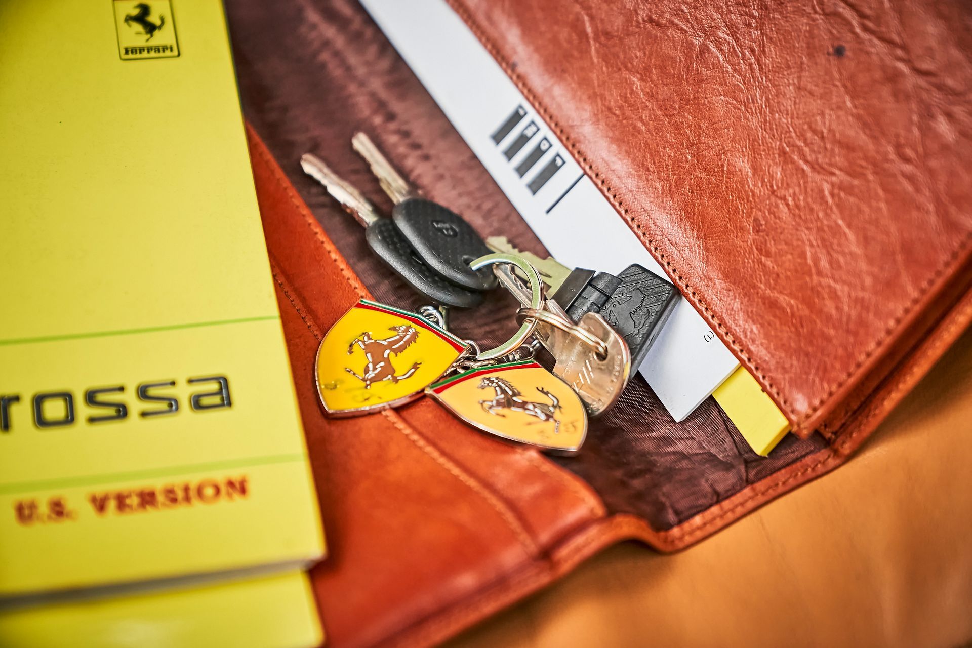A close up of a wallet with keys and a yellow book.