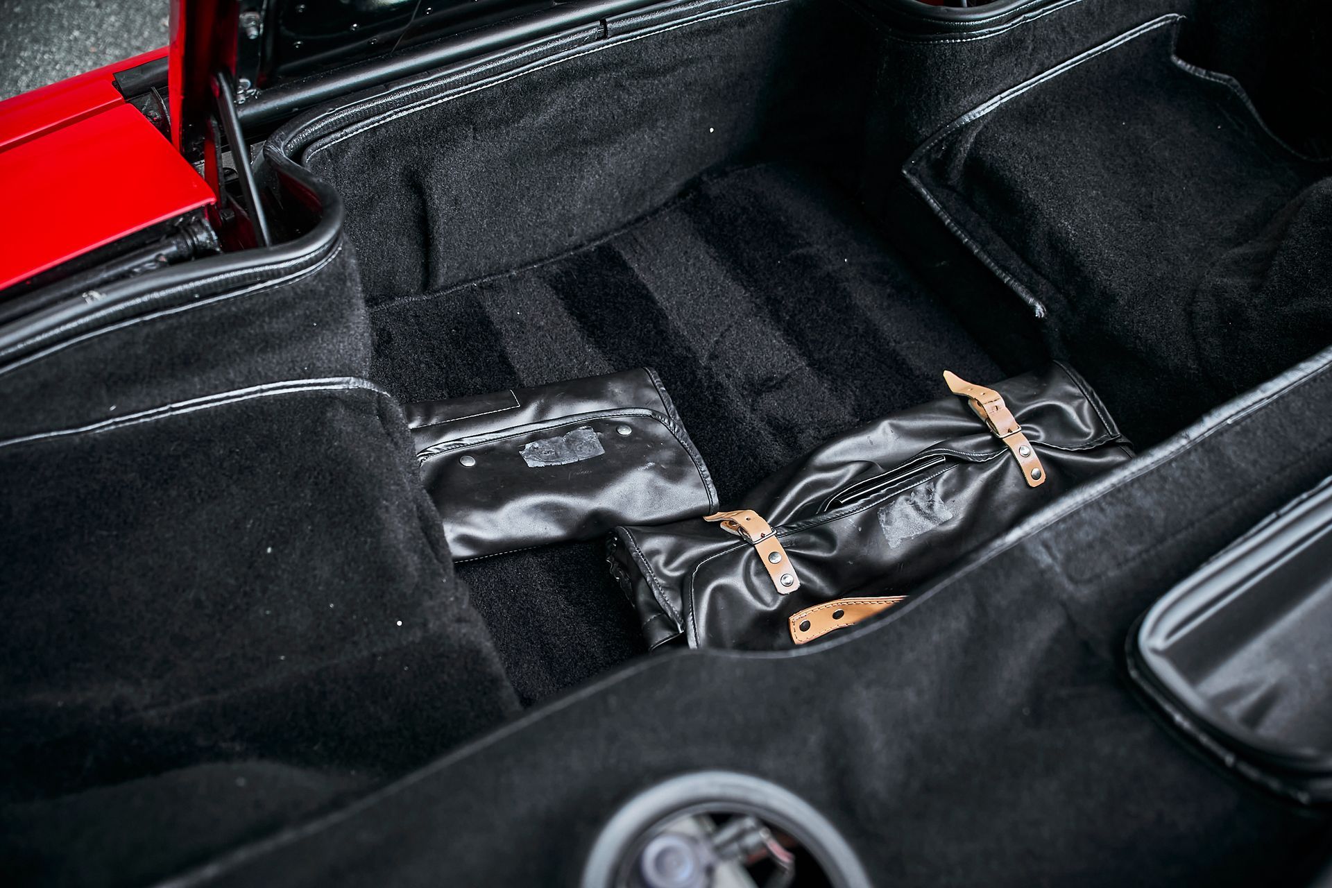 A close up of the trunk of a car with a red car in the background.