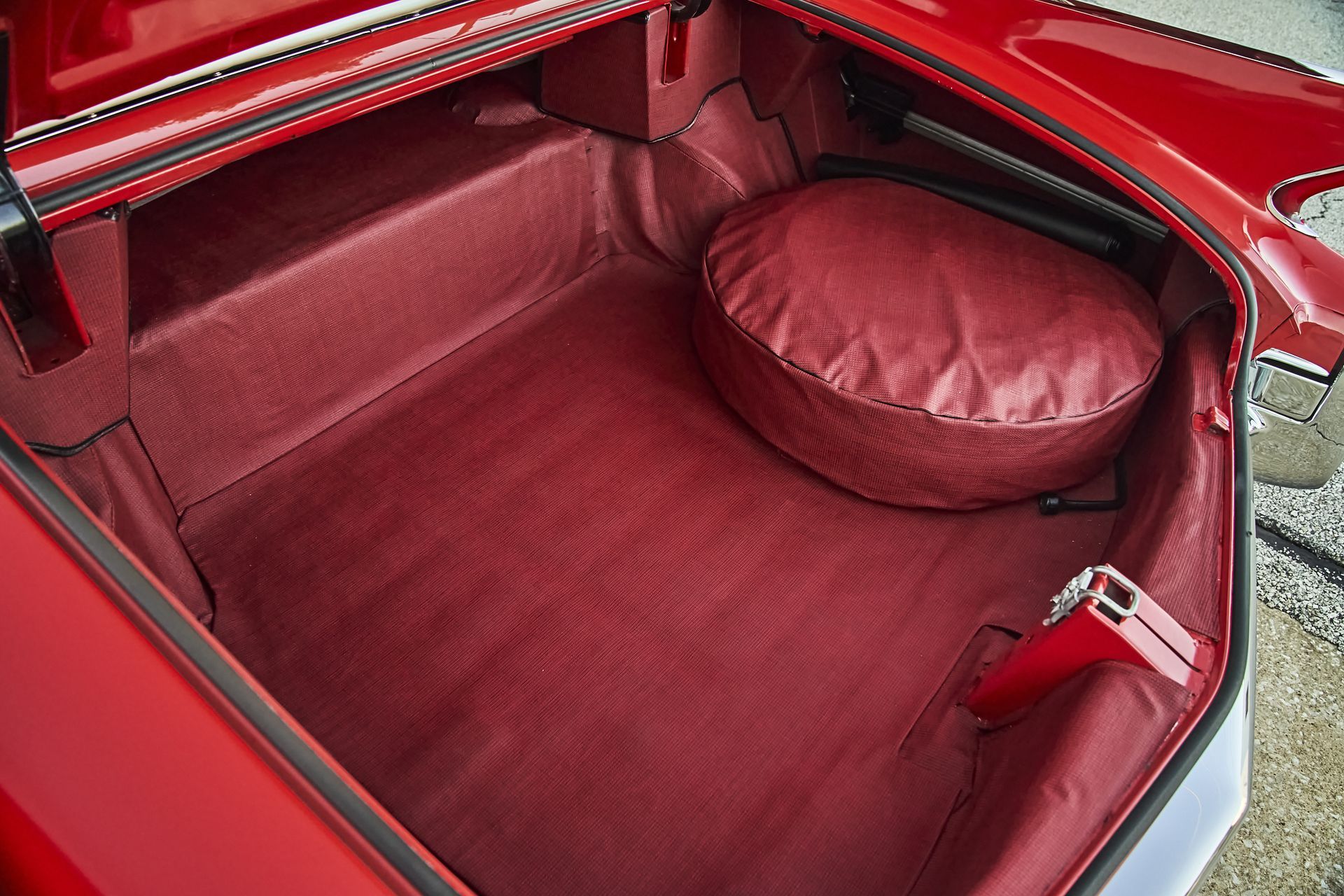 The trunk of a red car with a red tire cover
