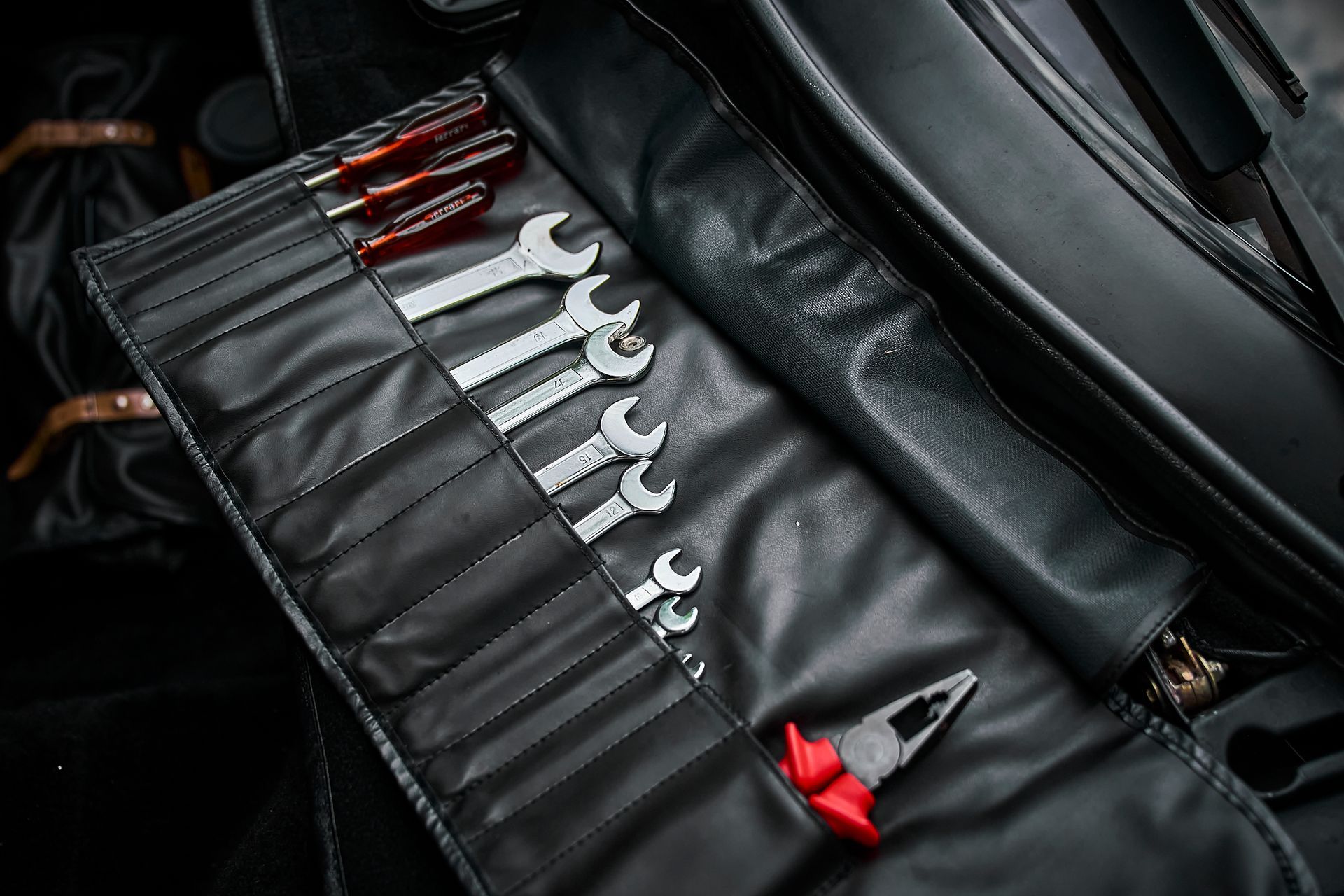 A black leather tool roll filled with wrenches and pliers.