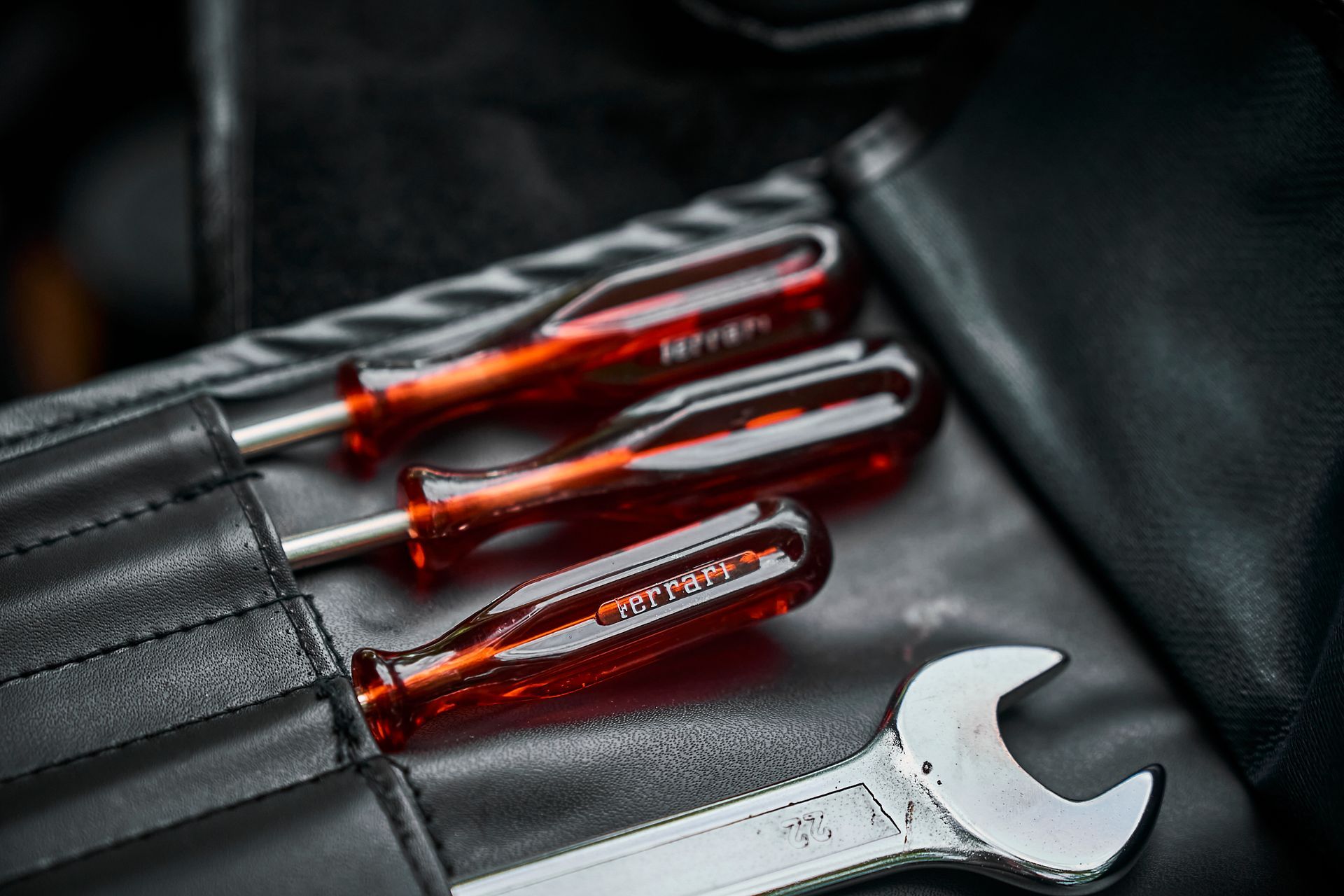 A pair of screwdrivers and a wrench are in a leather case.