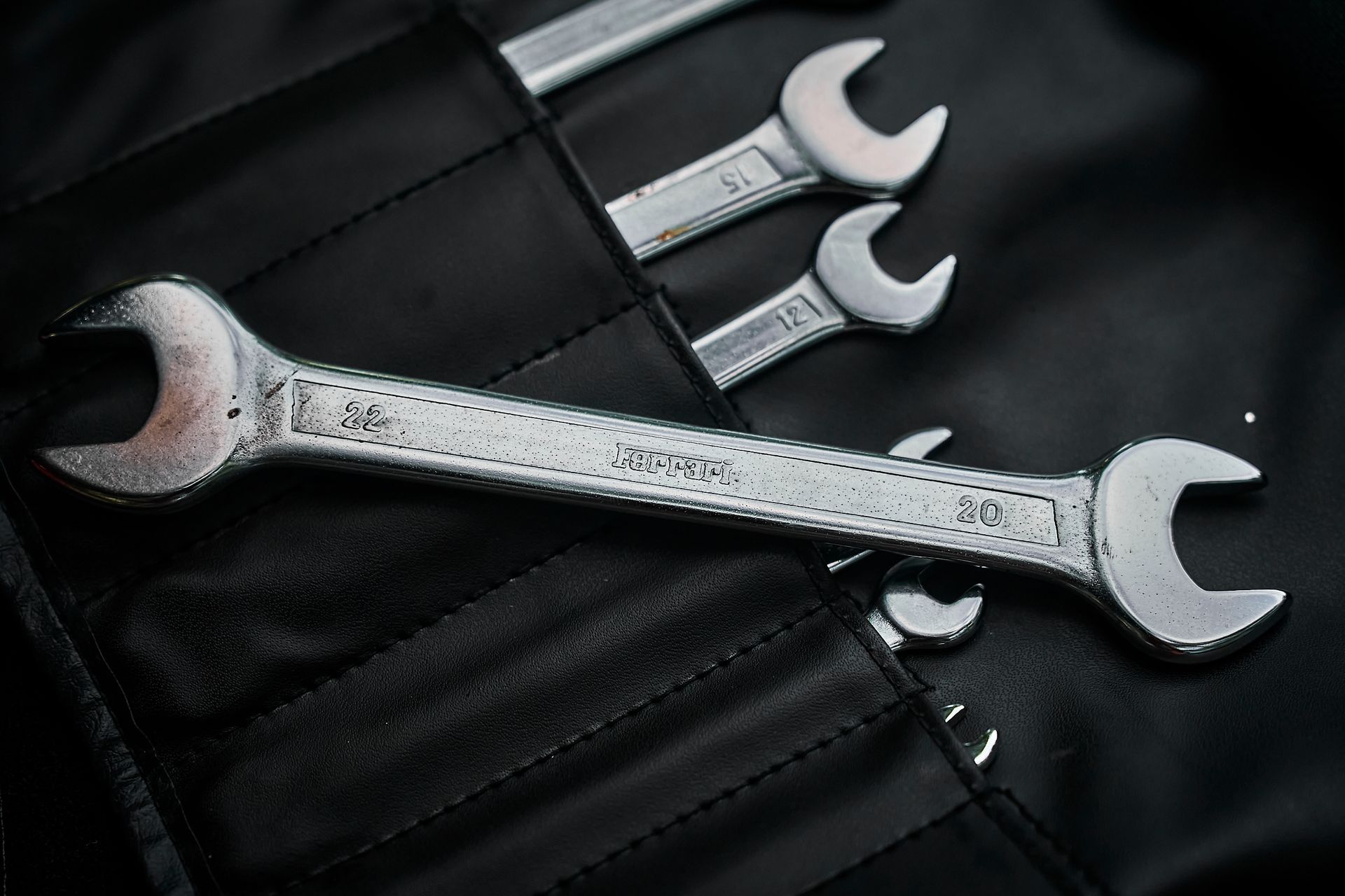 Three wrenches are sitting on top of each other on a black cloth.