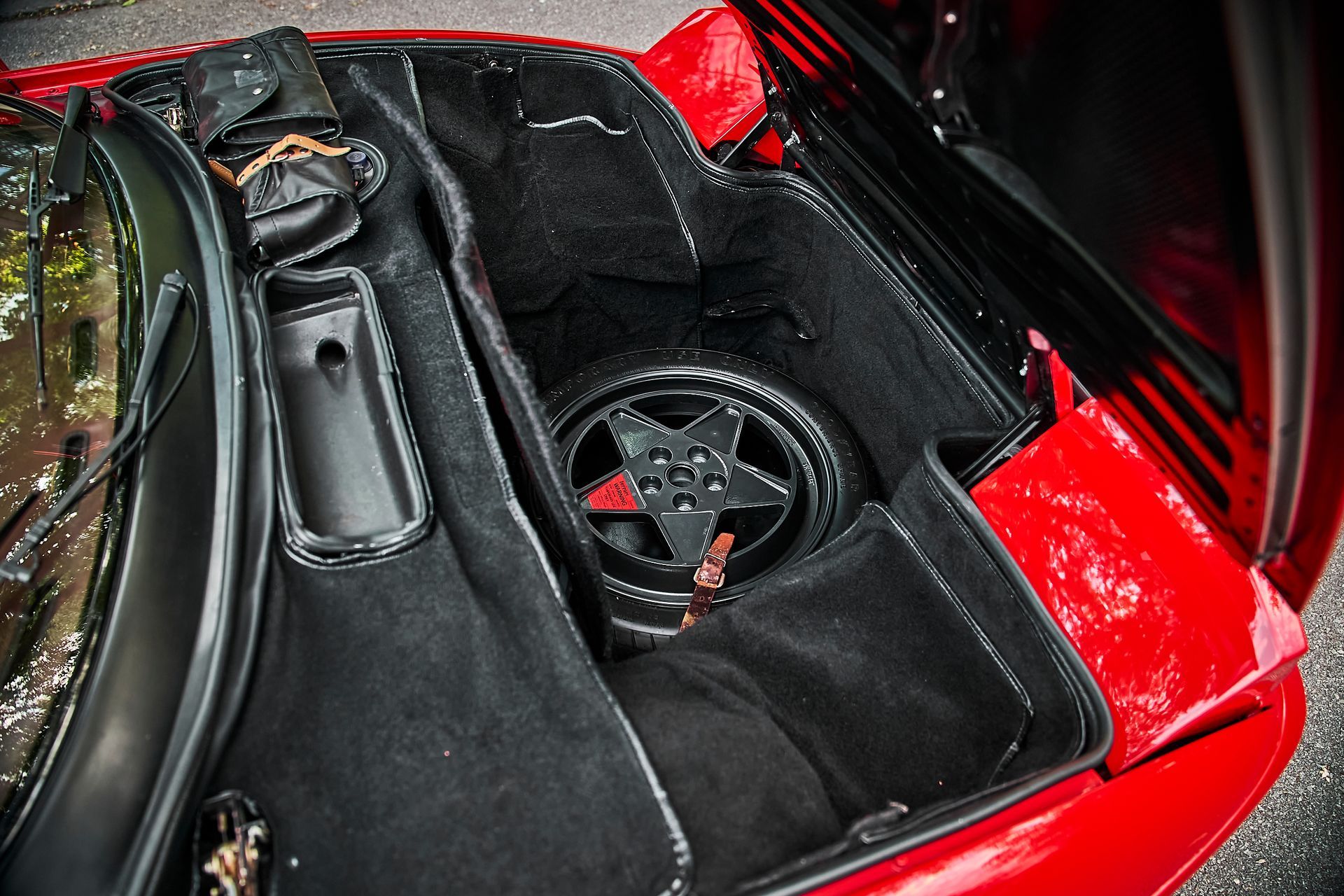 The trunk of a red sports car with the hood open.