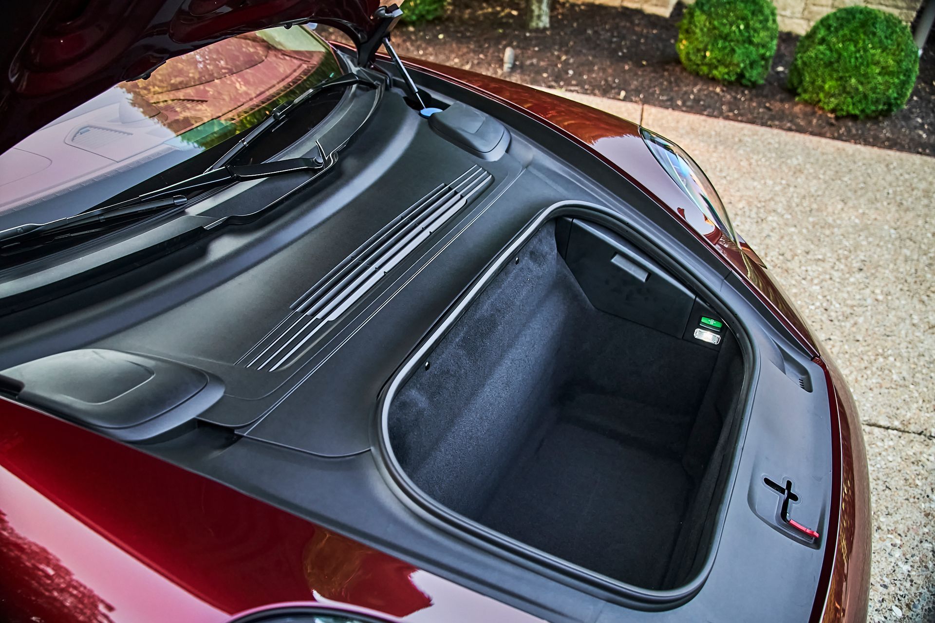 The trunk of a red sports car is open and empty.