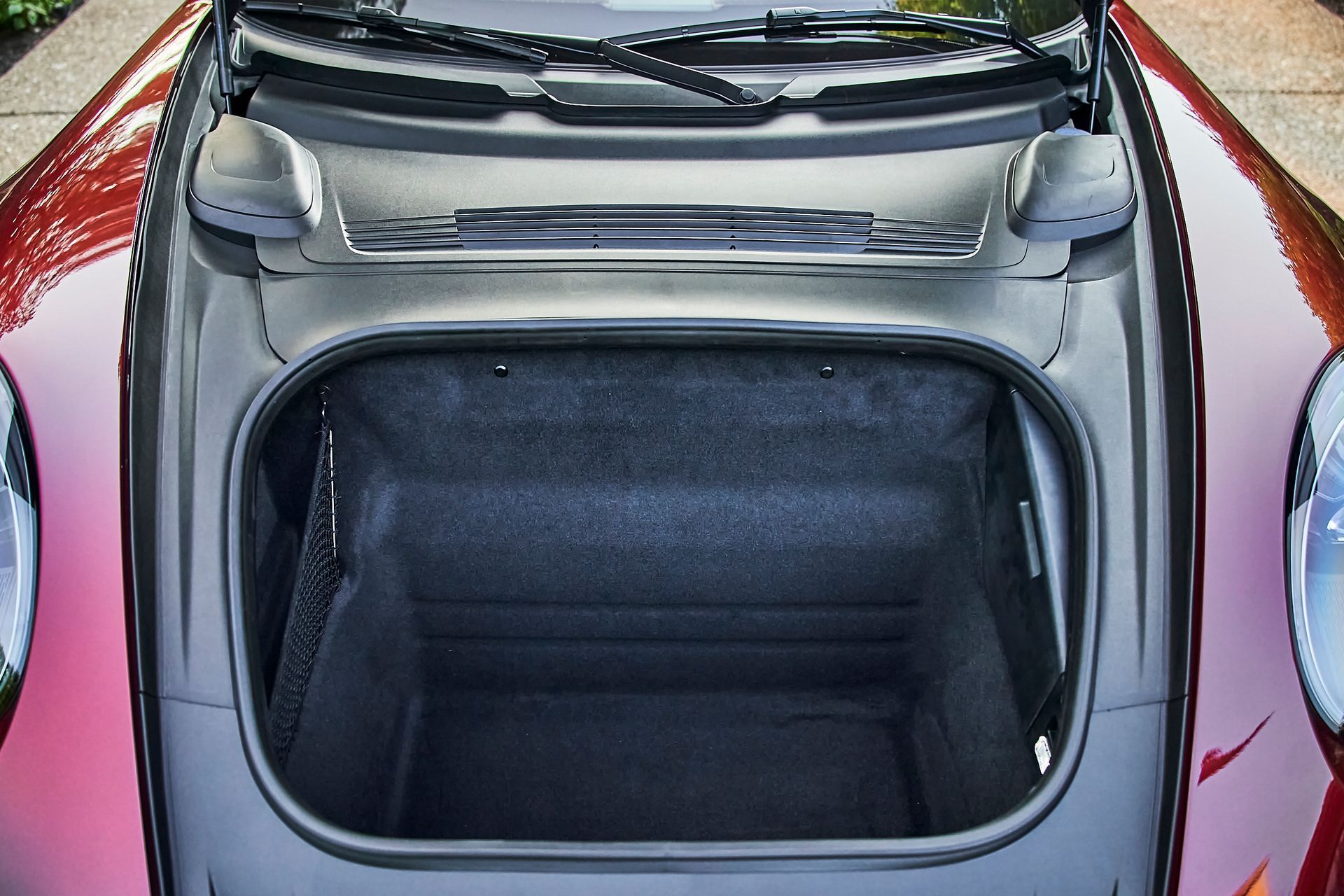 The trunk of a red car is open and empty