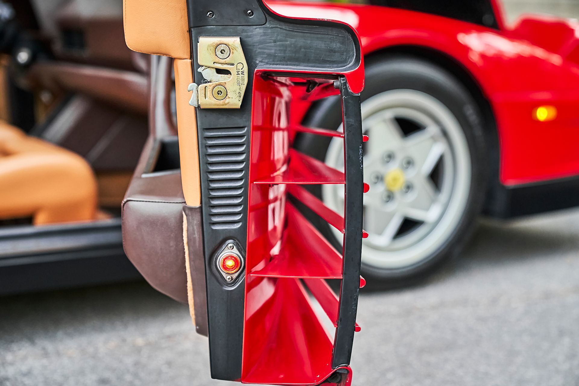 A red car is parked in front of a red fan.