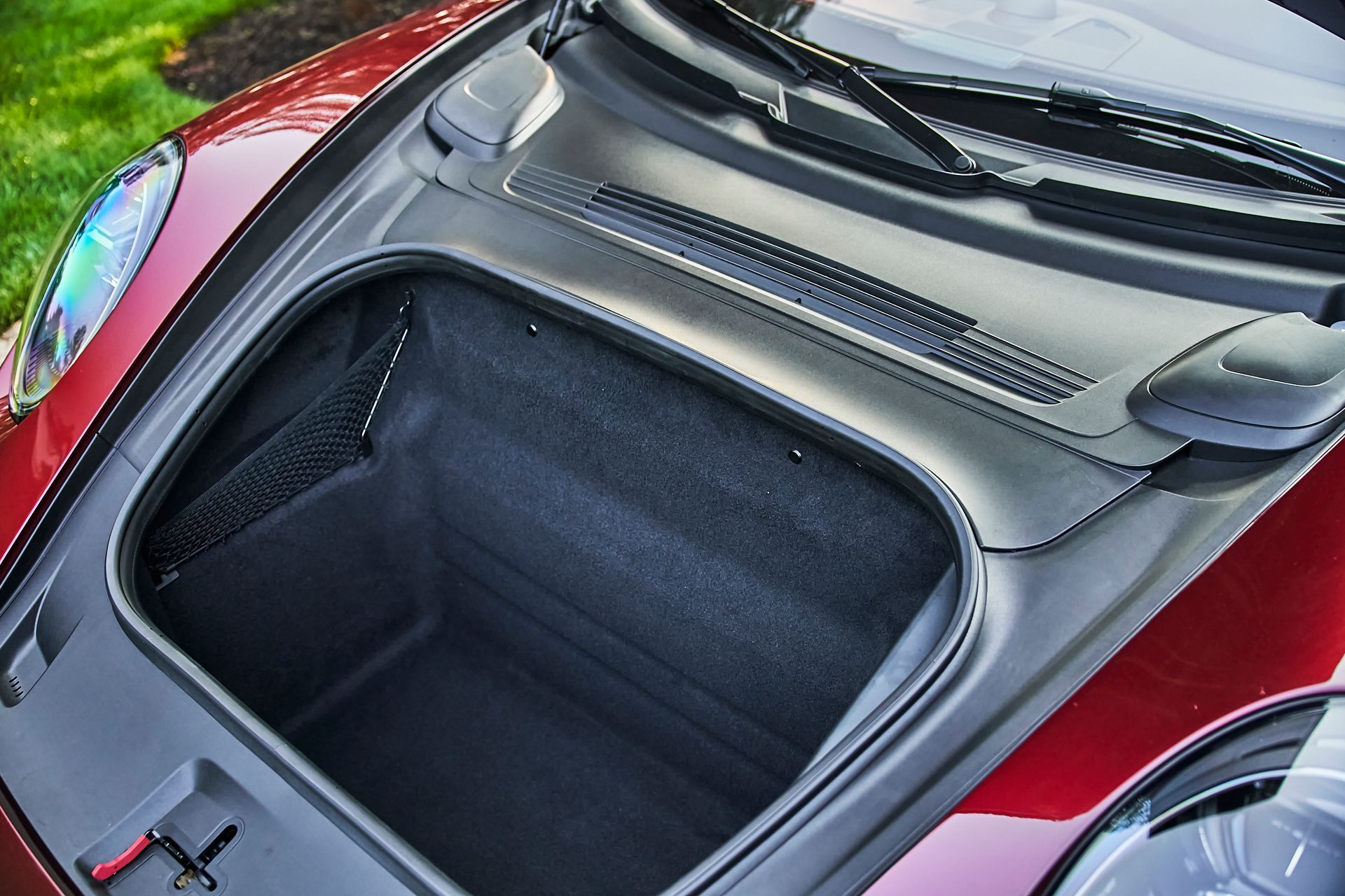 The trunk of a red sports car with the hood open