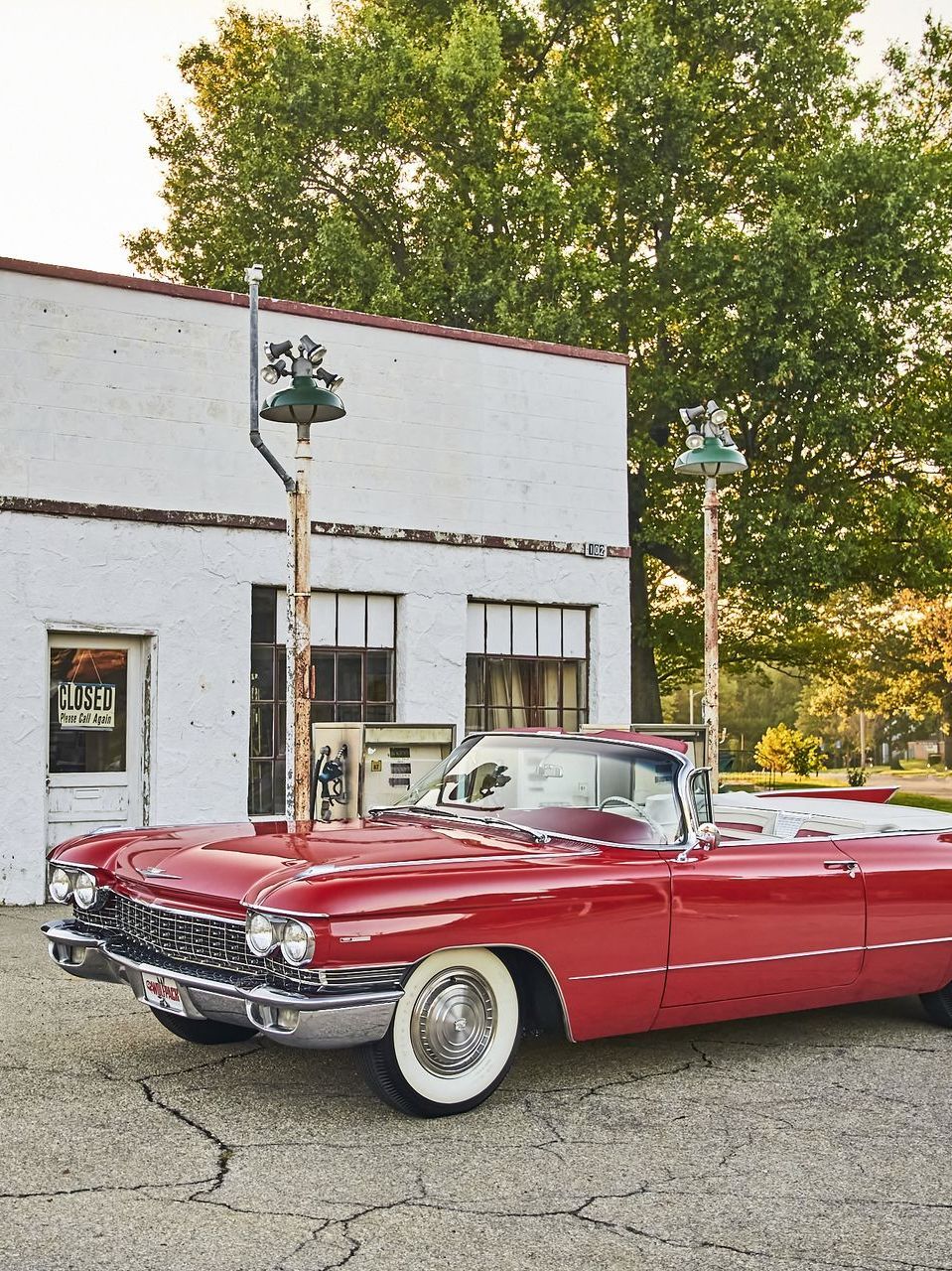 A red cadillac is parked in front of a white building