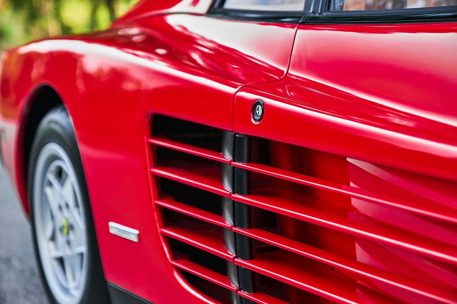 A close up of the front grille of a red sports car.