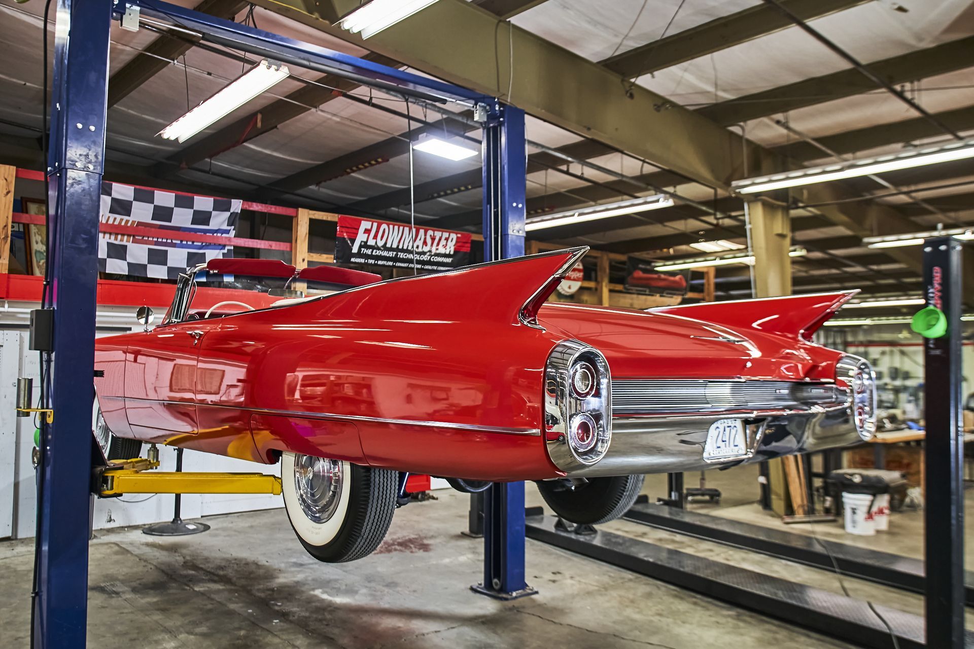 A red car is on a lift in a garage.