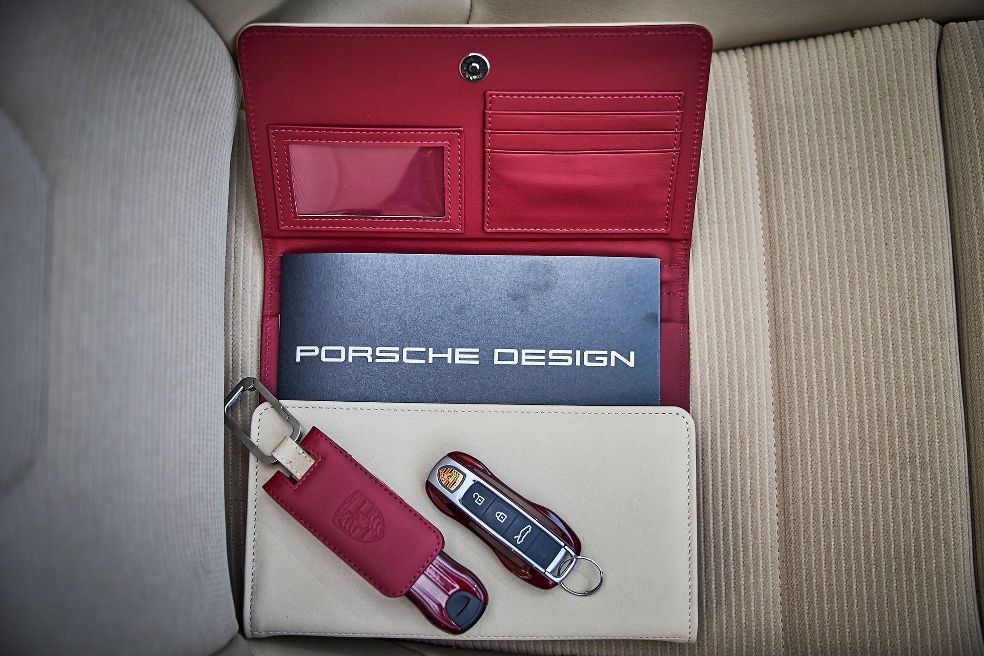 A red and white porsche design wallet with a keychain