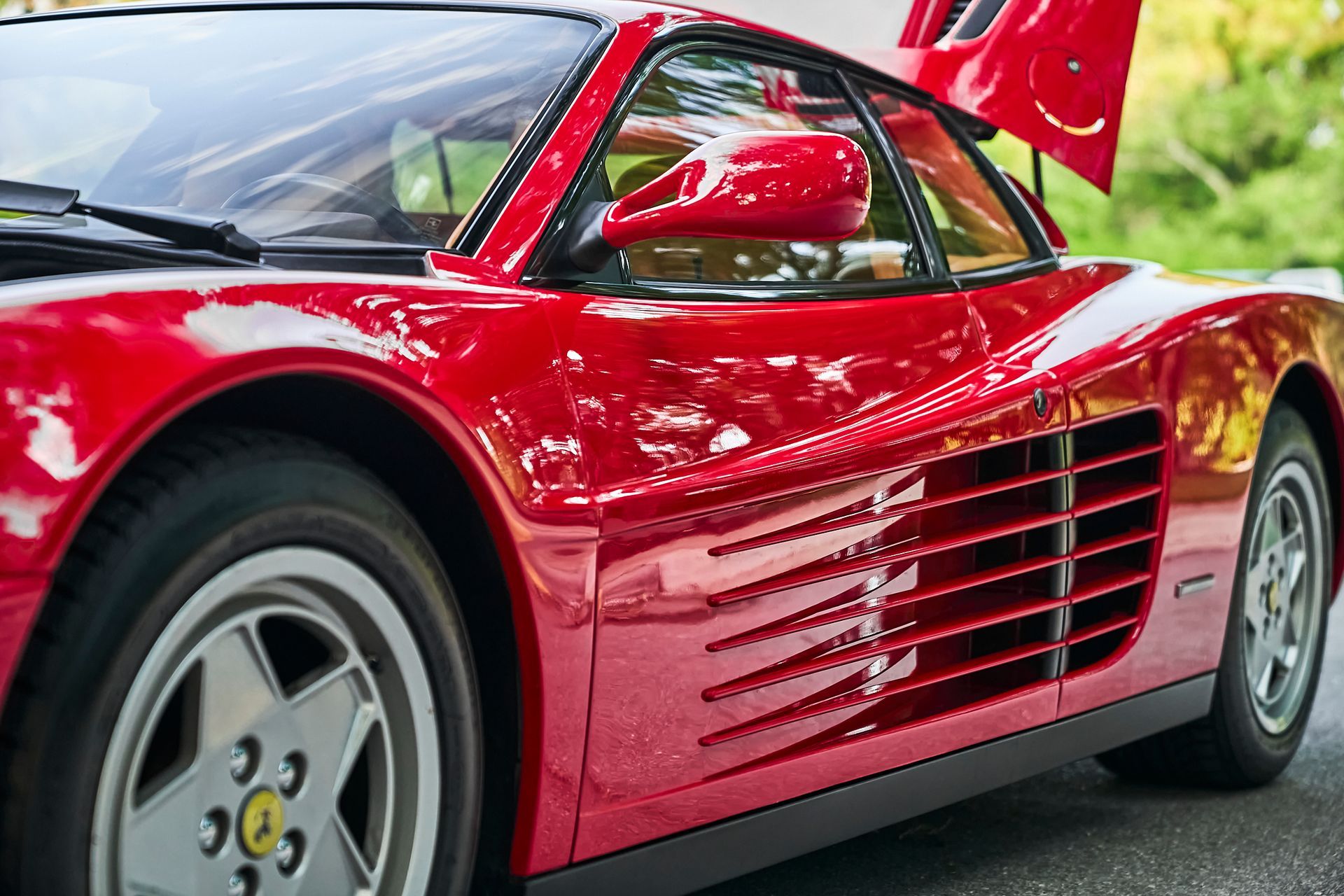 A red sports car with the hood up is parked on the side of the road.