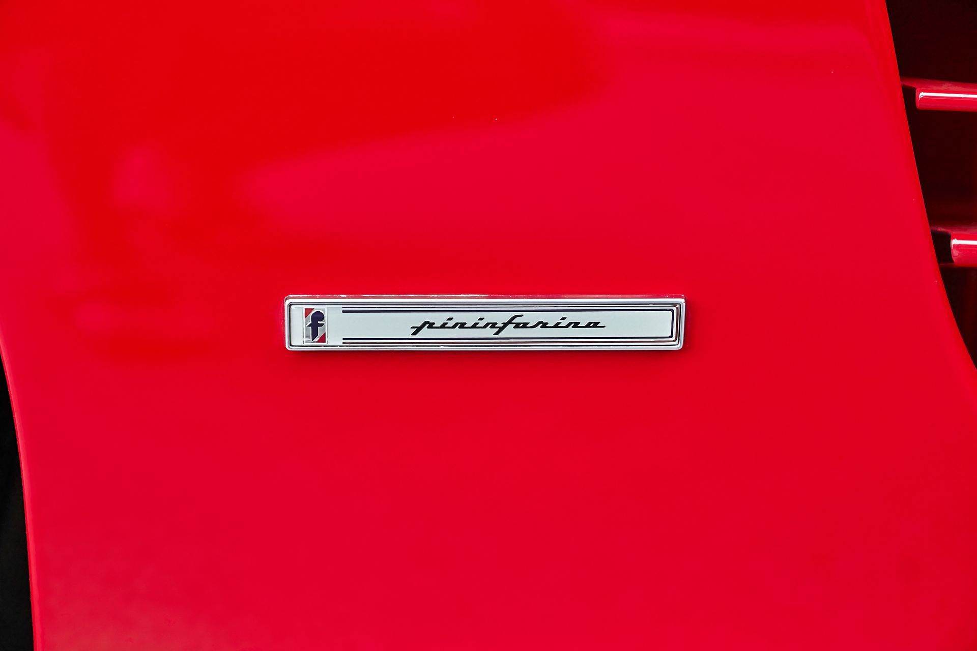 A close up of a red car with a badge on it.