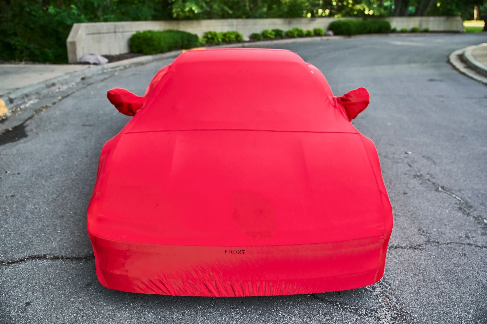 A red car cover is sitting on the side of a road.