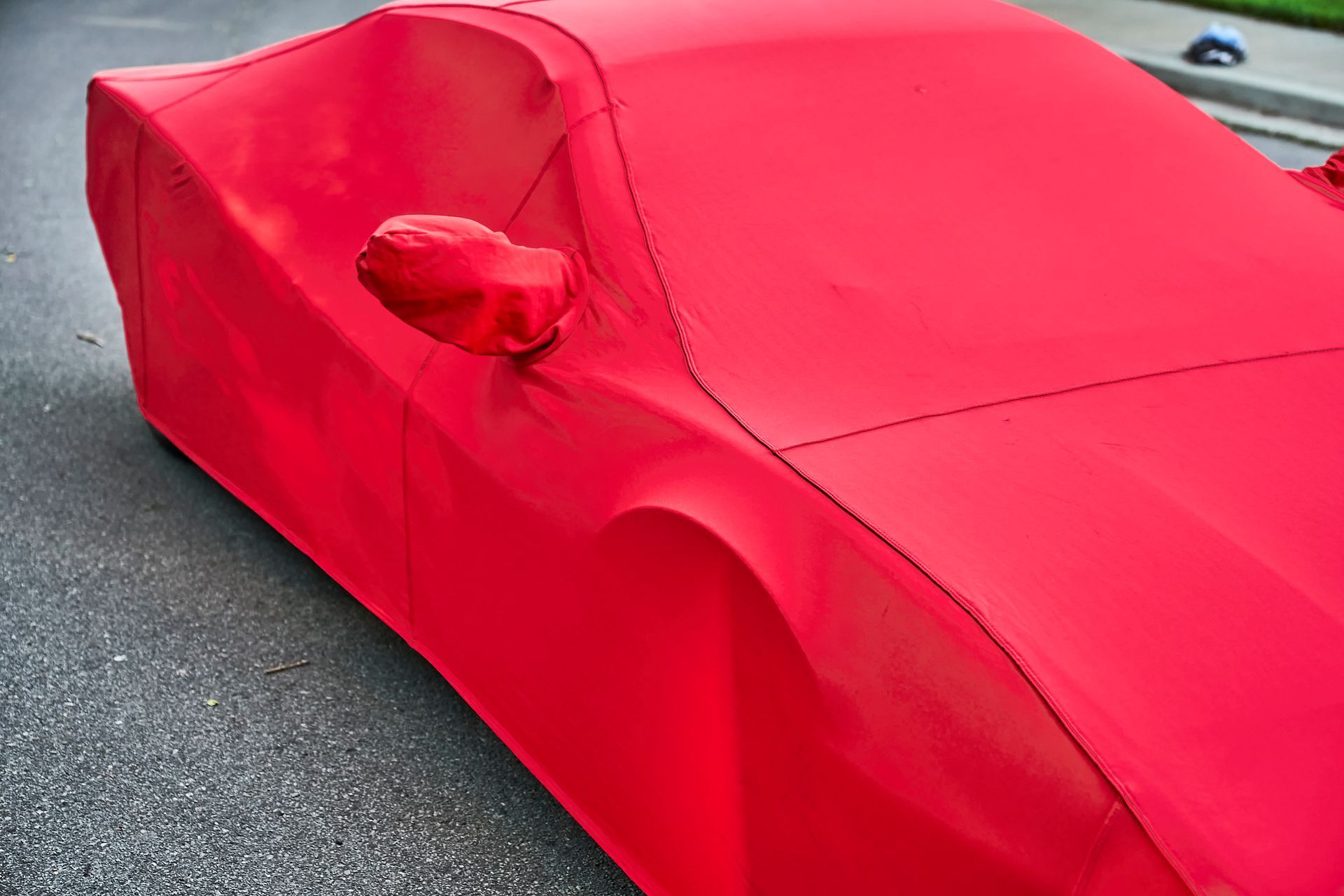 A red car is covered in a red cover.