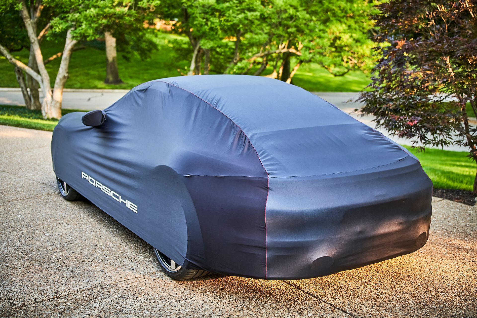 A car with a cover on it is parked in a driveway.