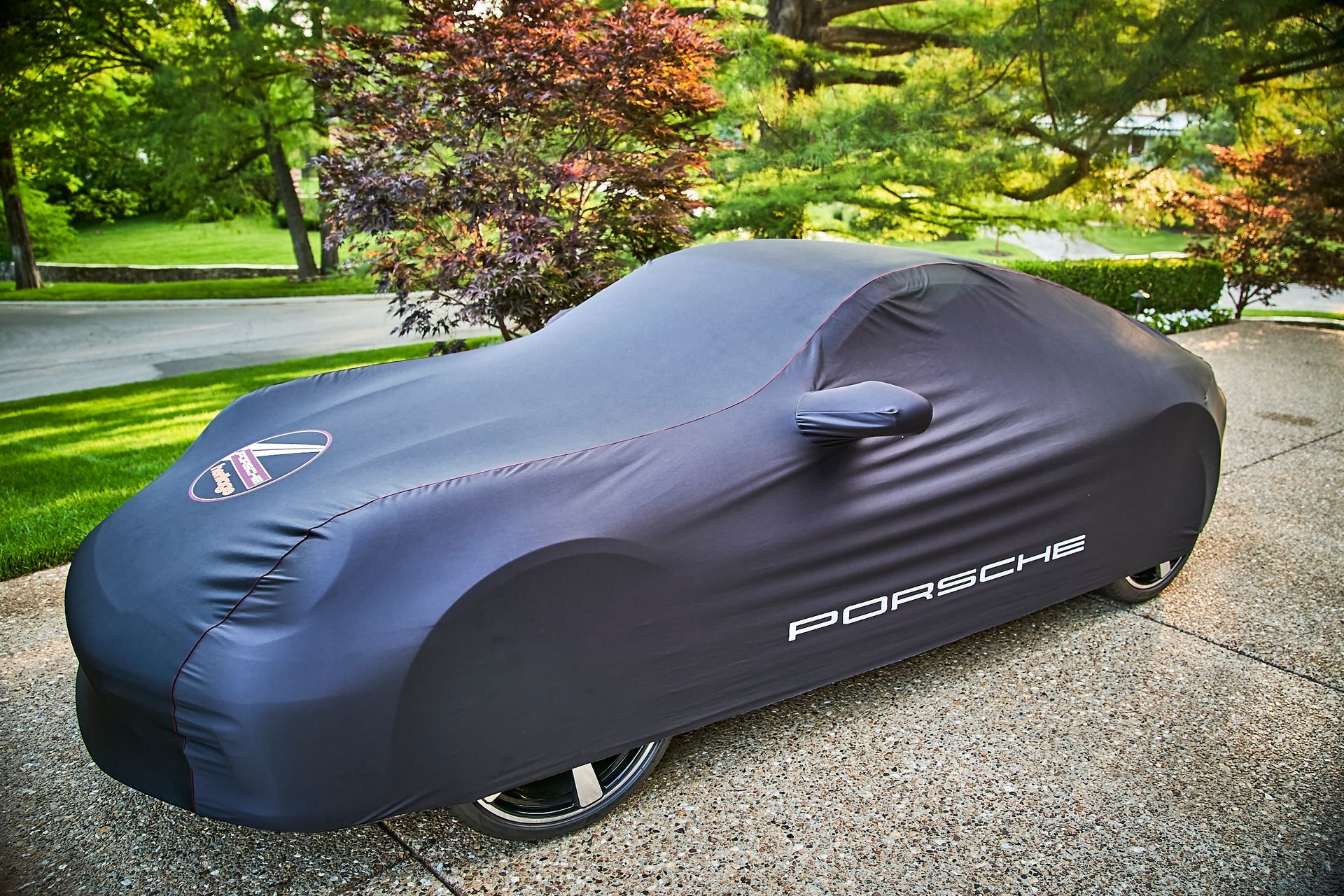 A car with a cover on it is parked in a driveway