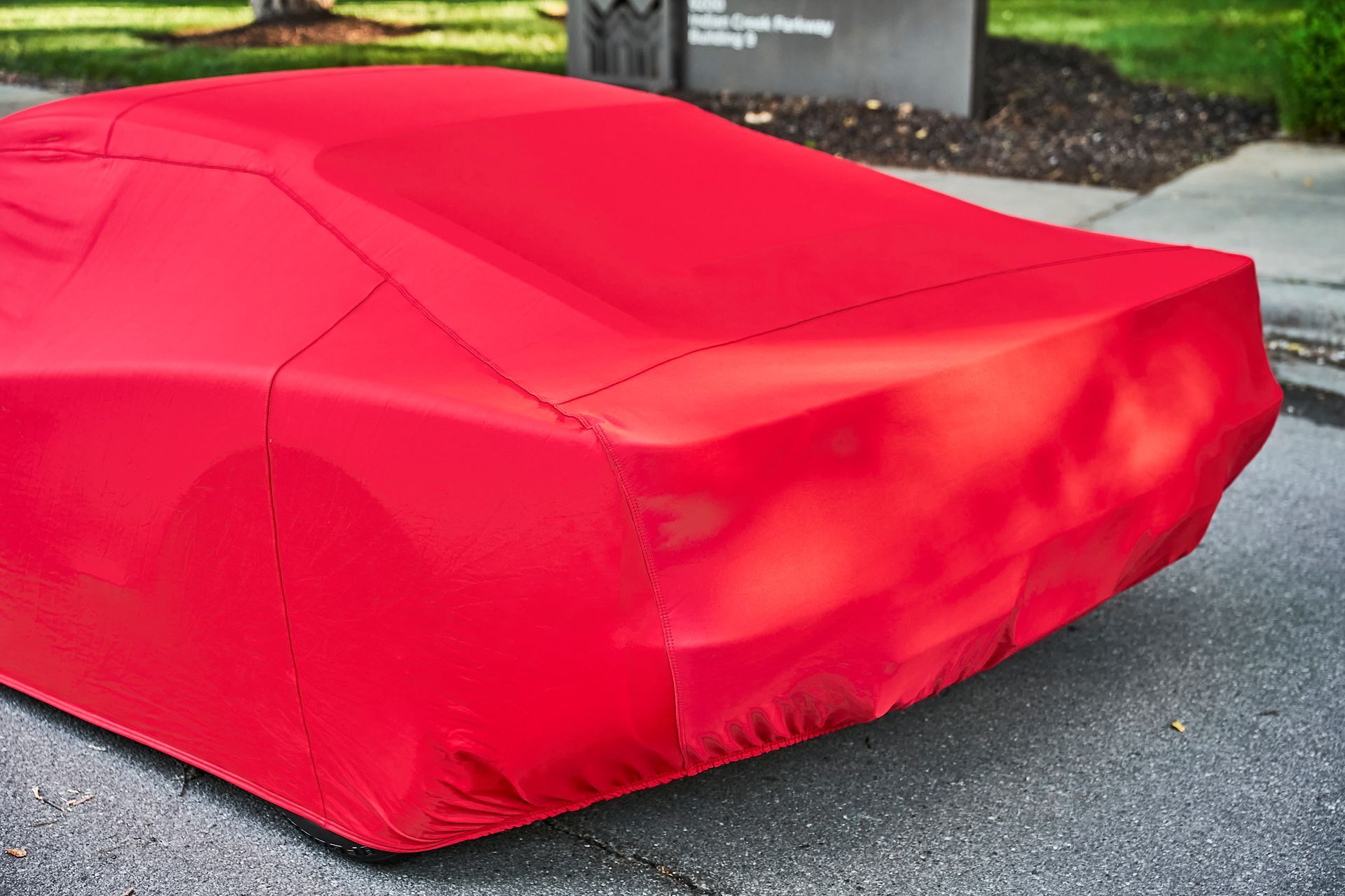 A red car cover is sitting on the side of the road.