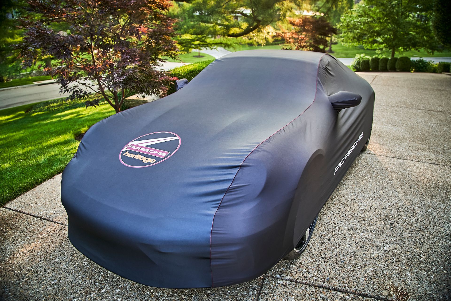 A black car with a cover on it is parked on a driveway