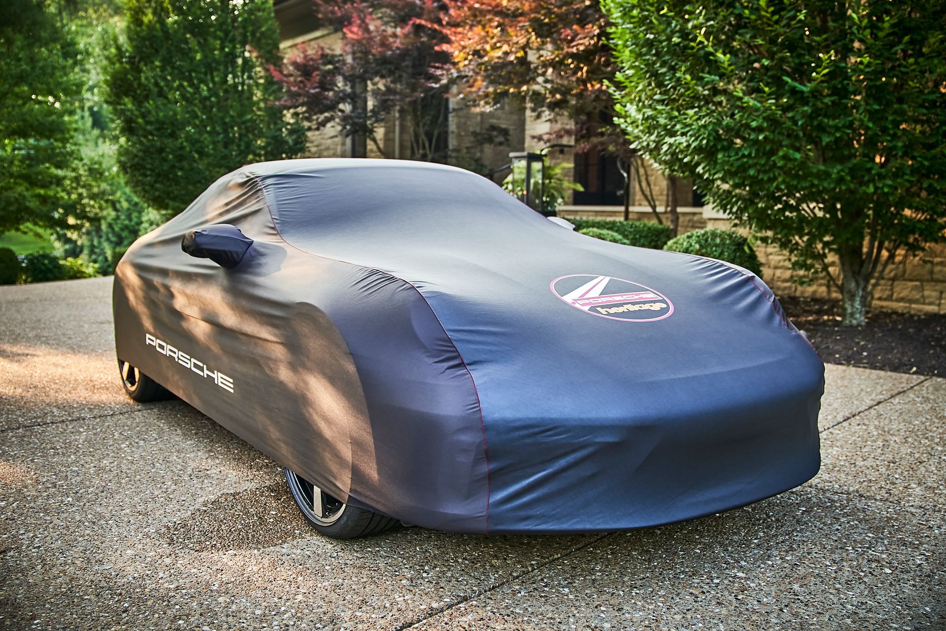 A car with a cover on it is parked in a driveway.