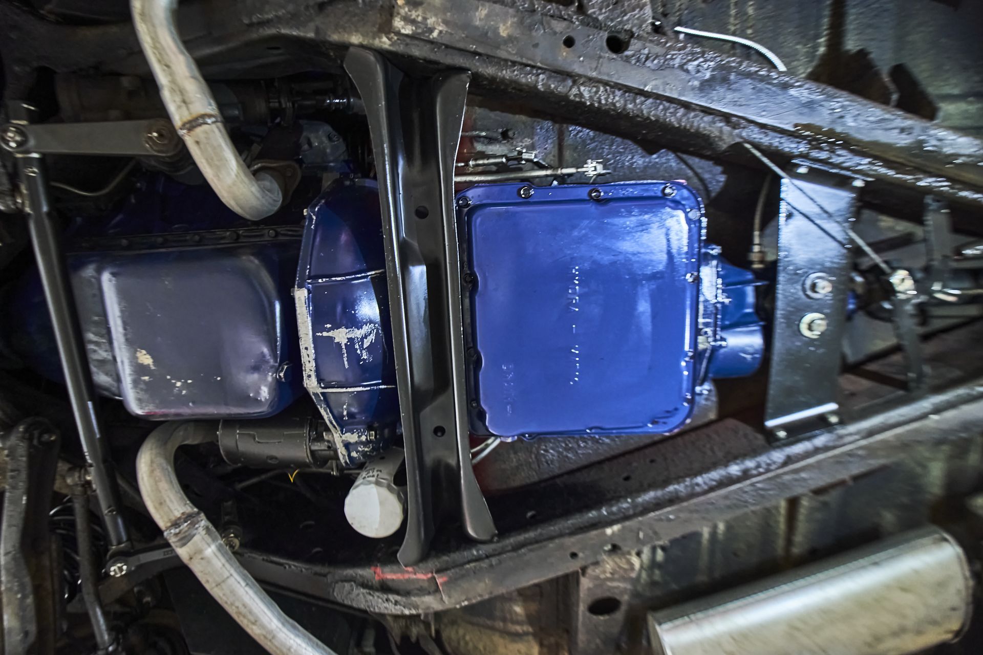 A blue engine is sitting underneath a car.