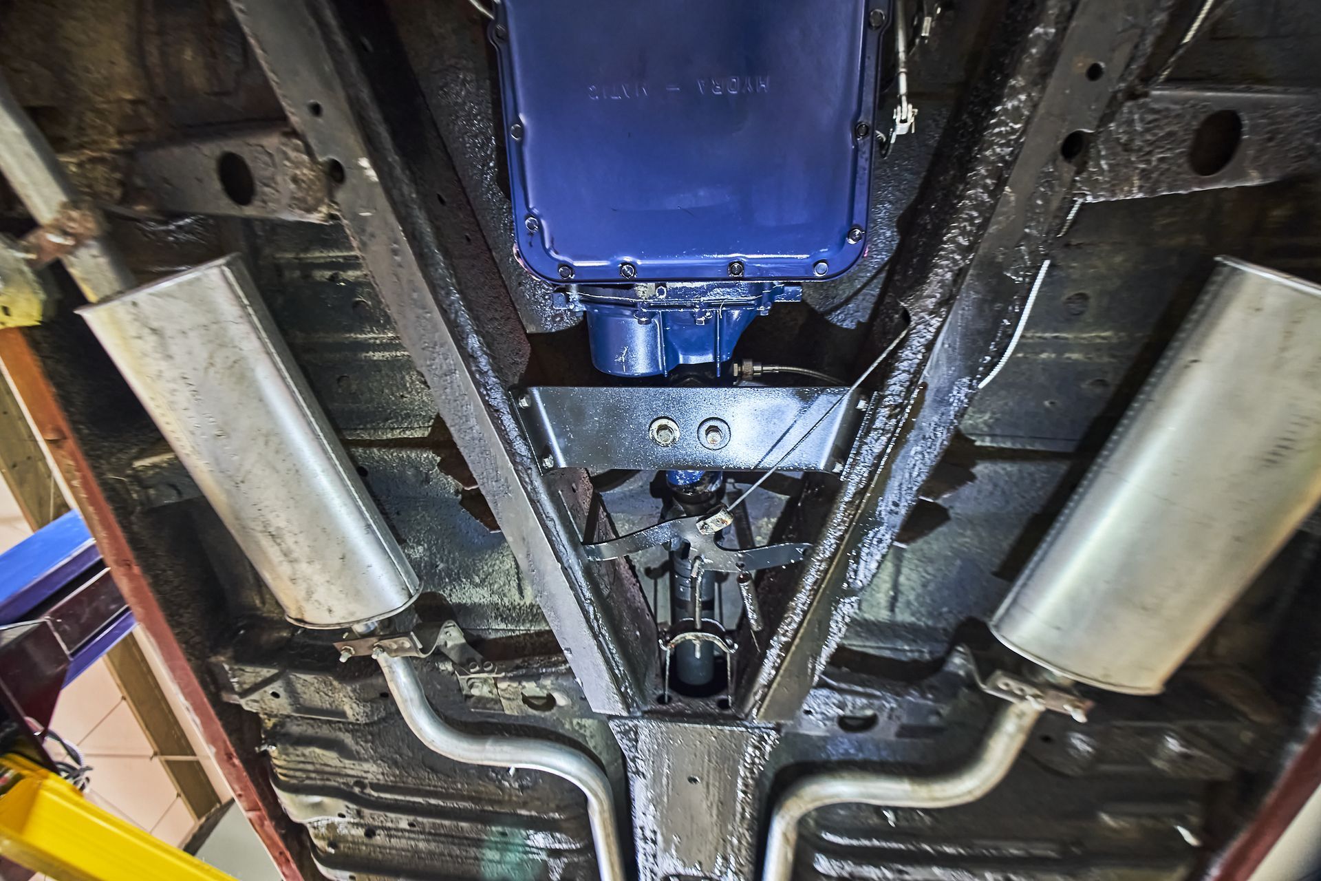 The underside of a car with a transmission and exhaust pipes.