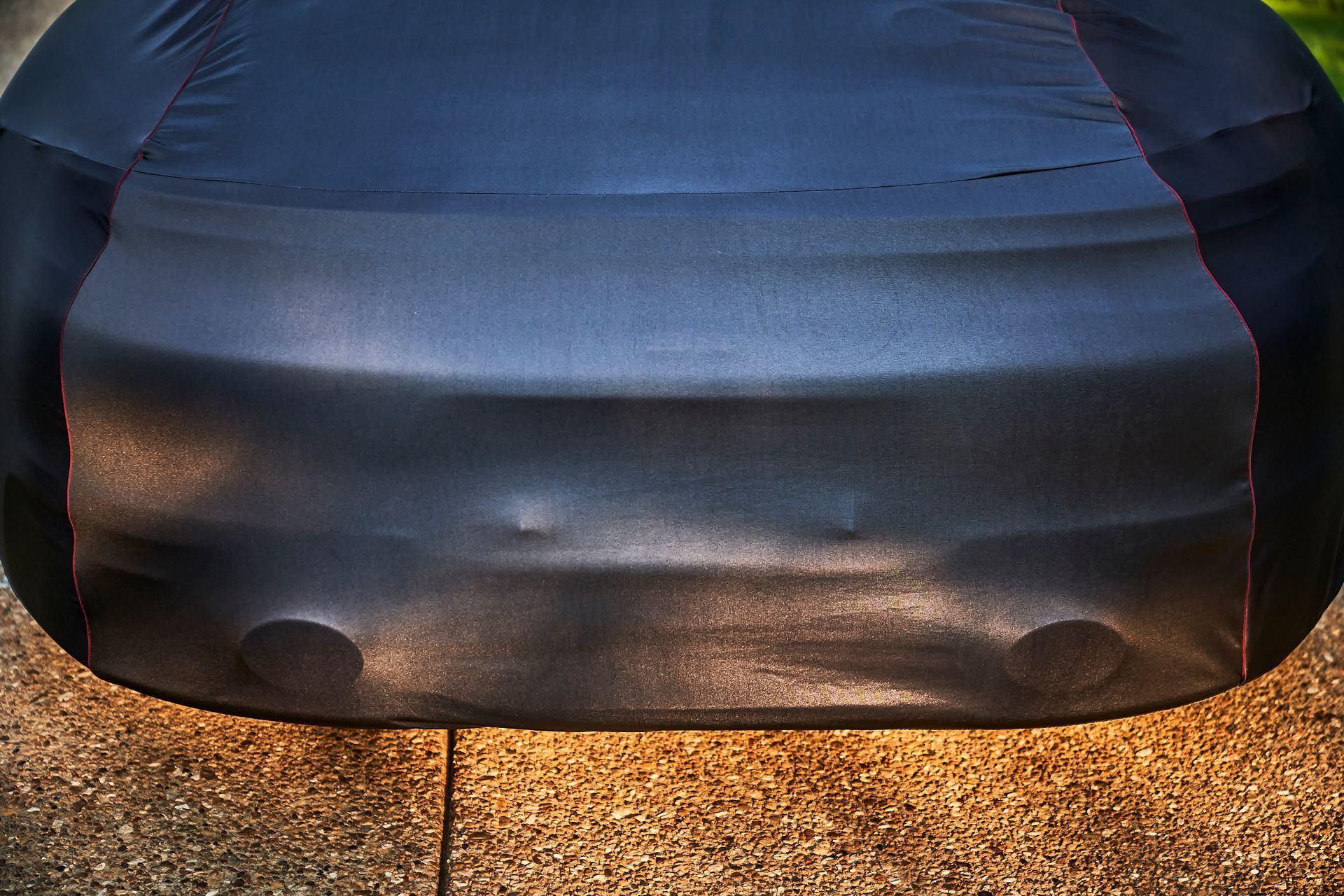 A black car is covered in a black cover