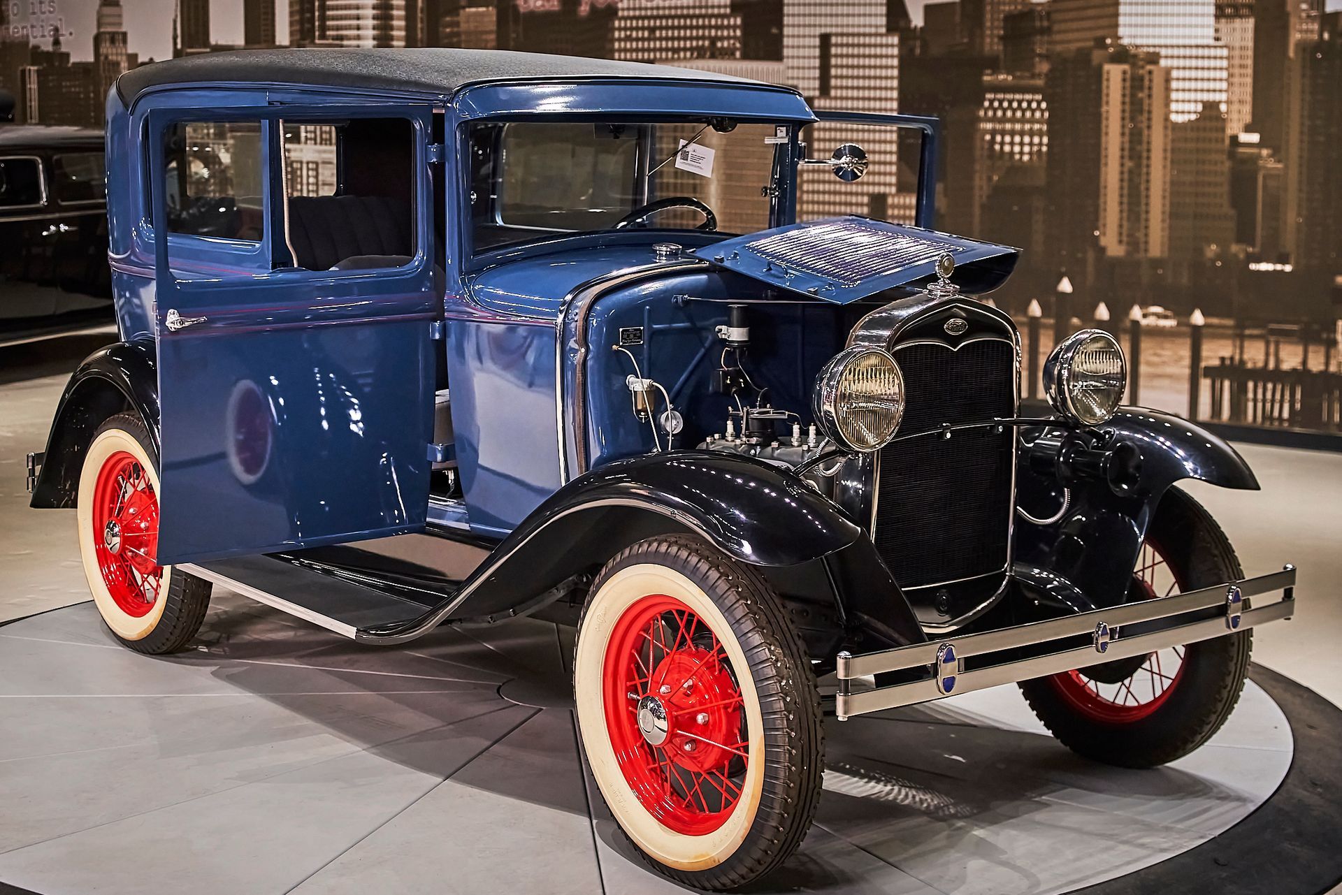 An old blue car with red wheels and white tires