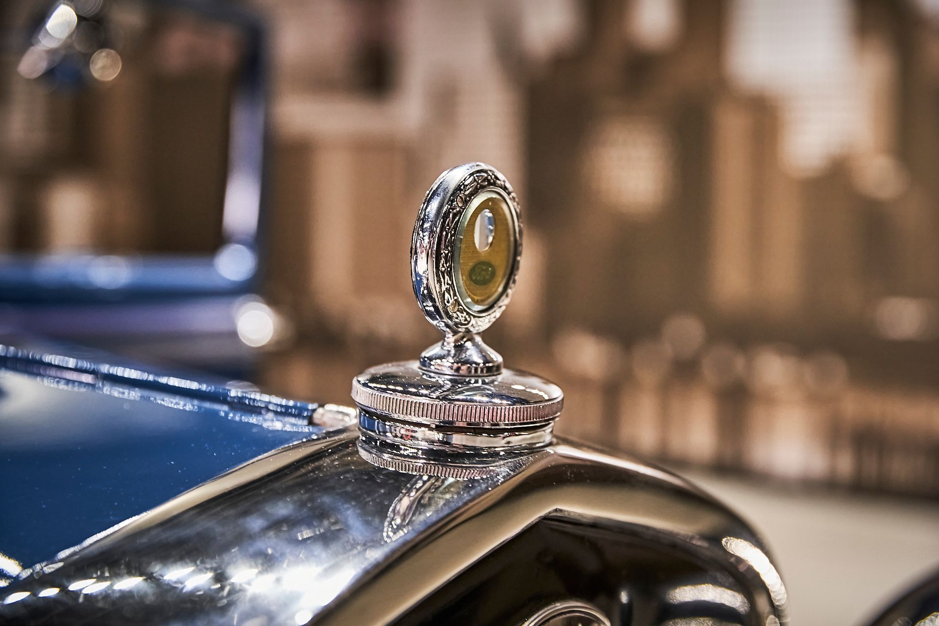 A close up of a car hood ornament on a blue car.
