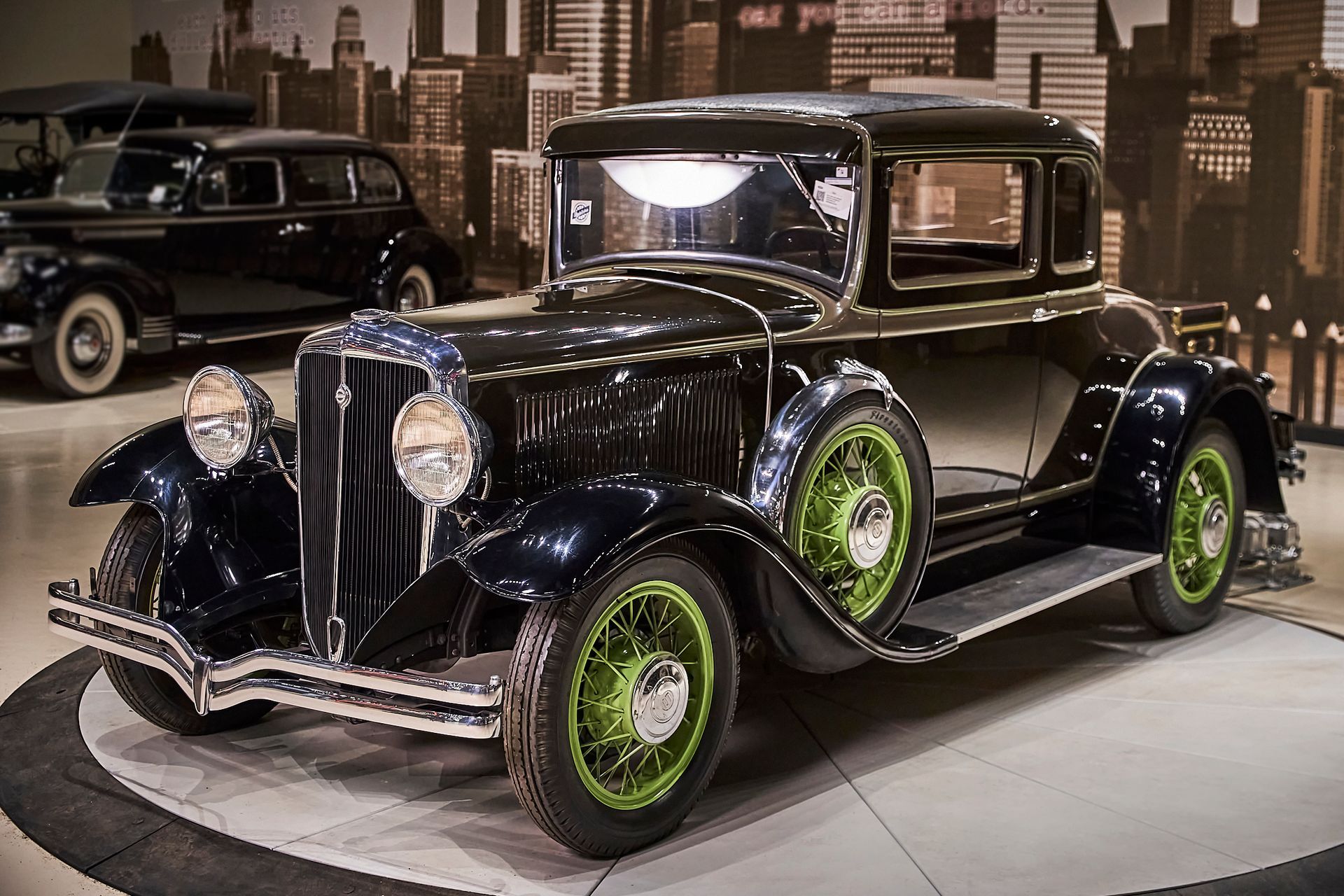 A black car with green wheels is parked in a garage.