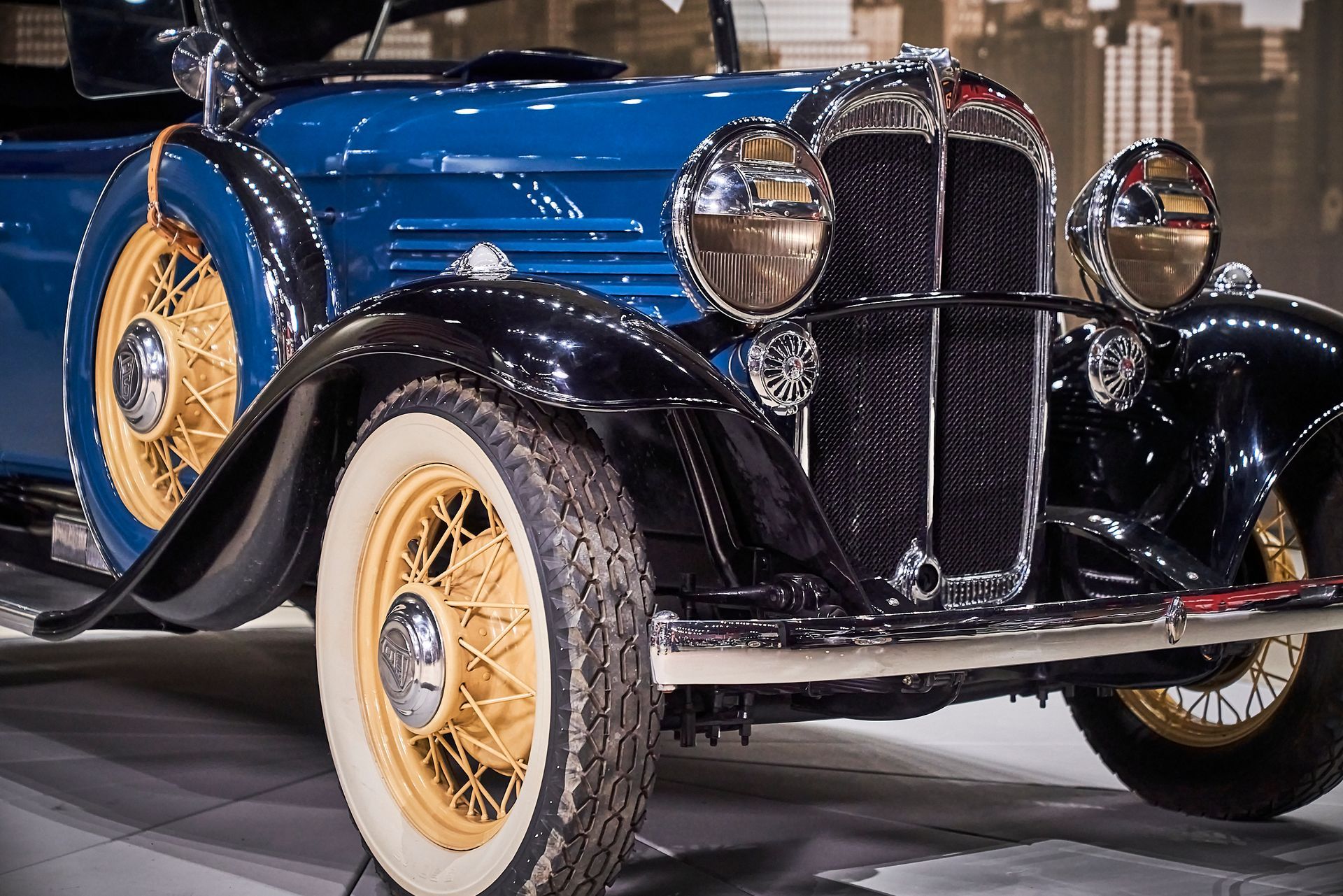 A blue and black vintage car is parked on a concrete floor.