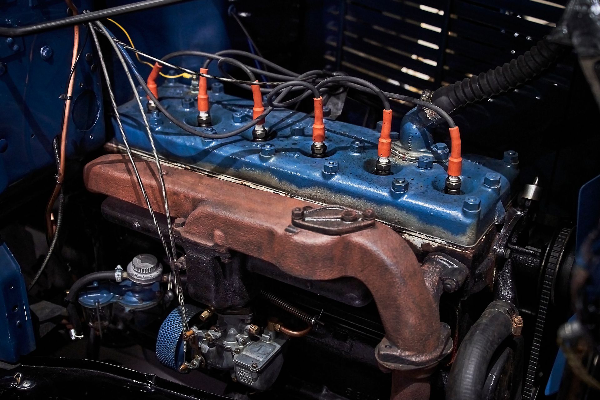 A close up of a blue car engine with orange spark plugs