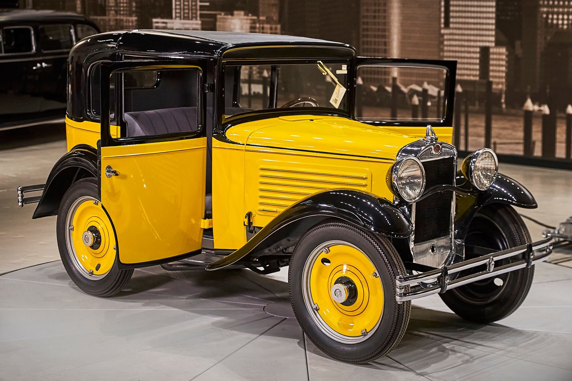 An old yellow and black car is parked in a garage.