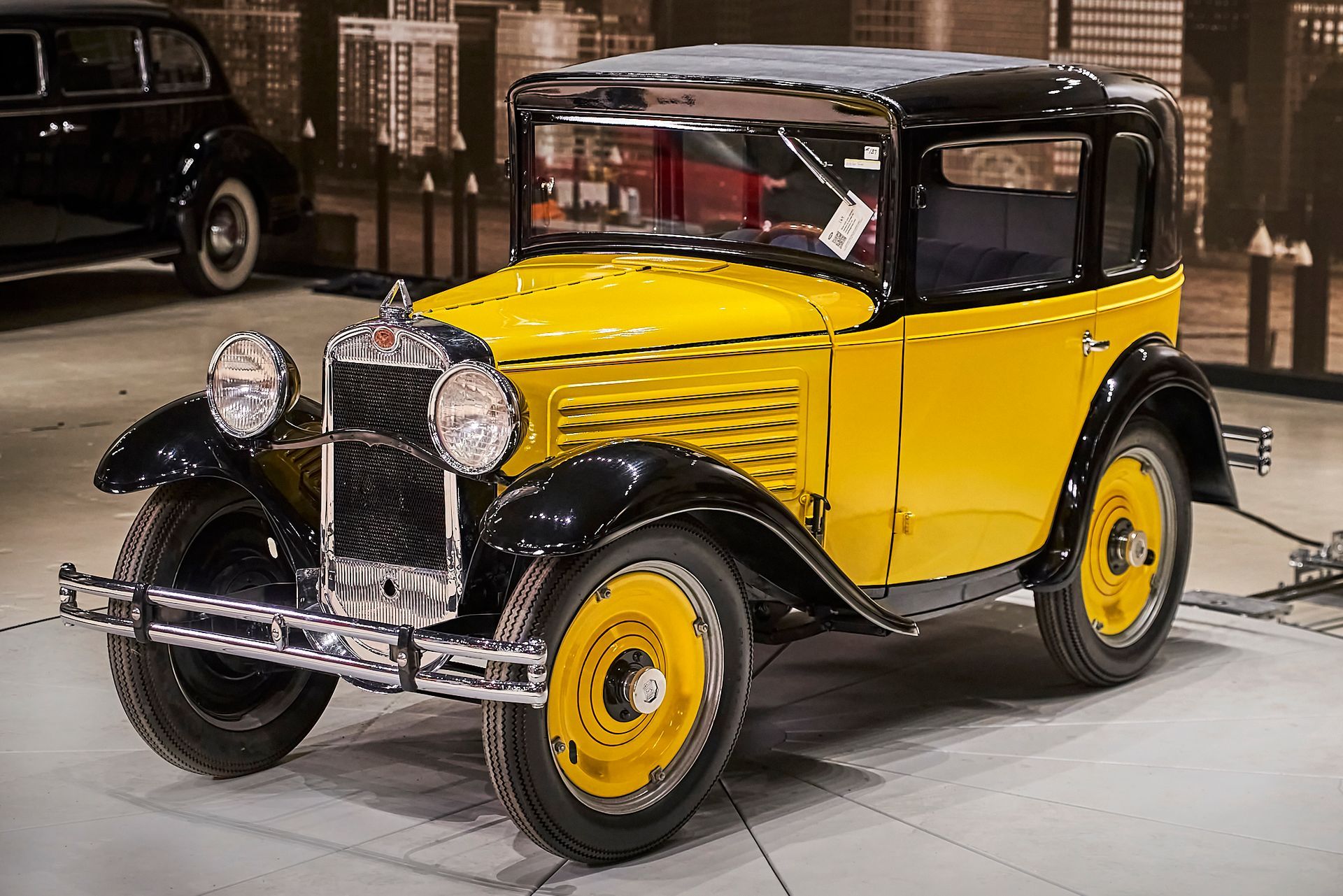 An old yellow car is parked in a garage.
