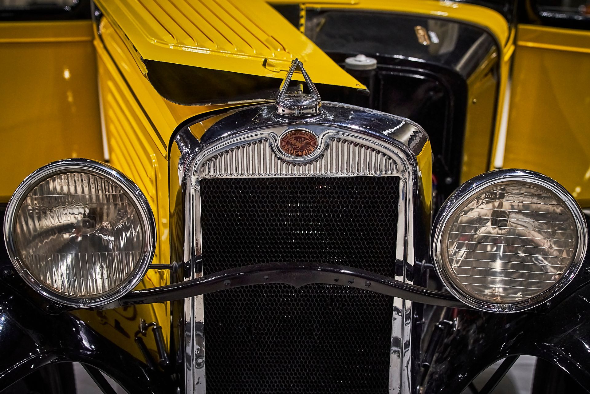 A close up of the front of an old yellow car