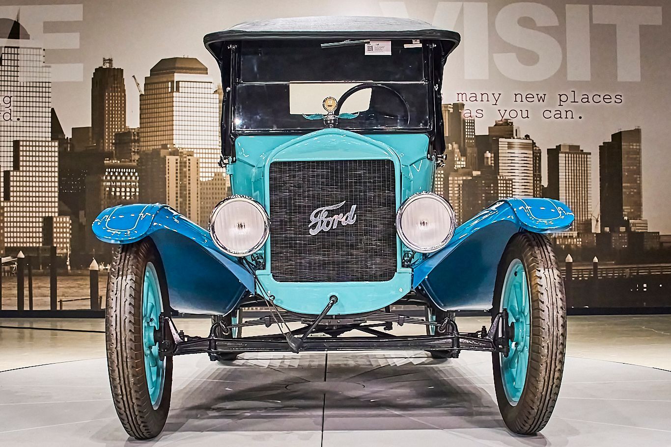 A blue ford car is parked in front of a city skyline