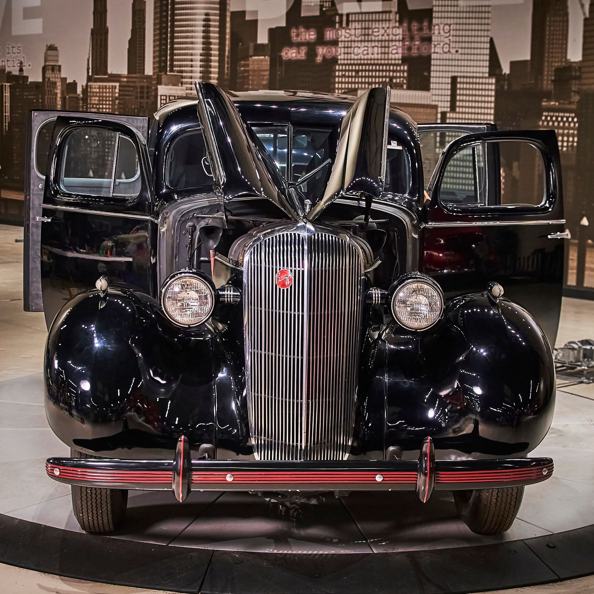 A black car with the doors open and a city in the background