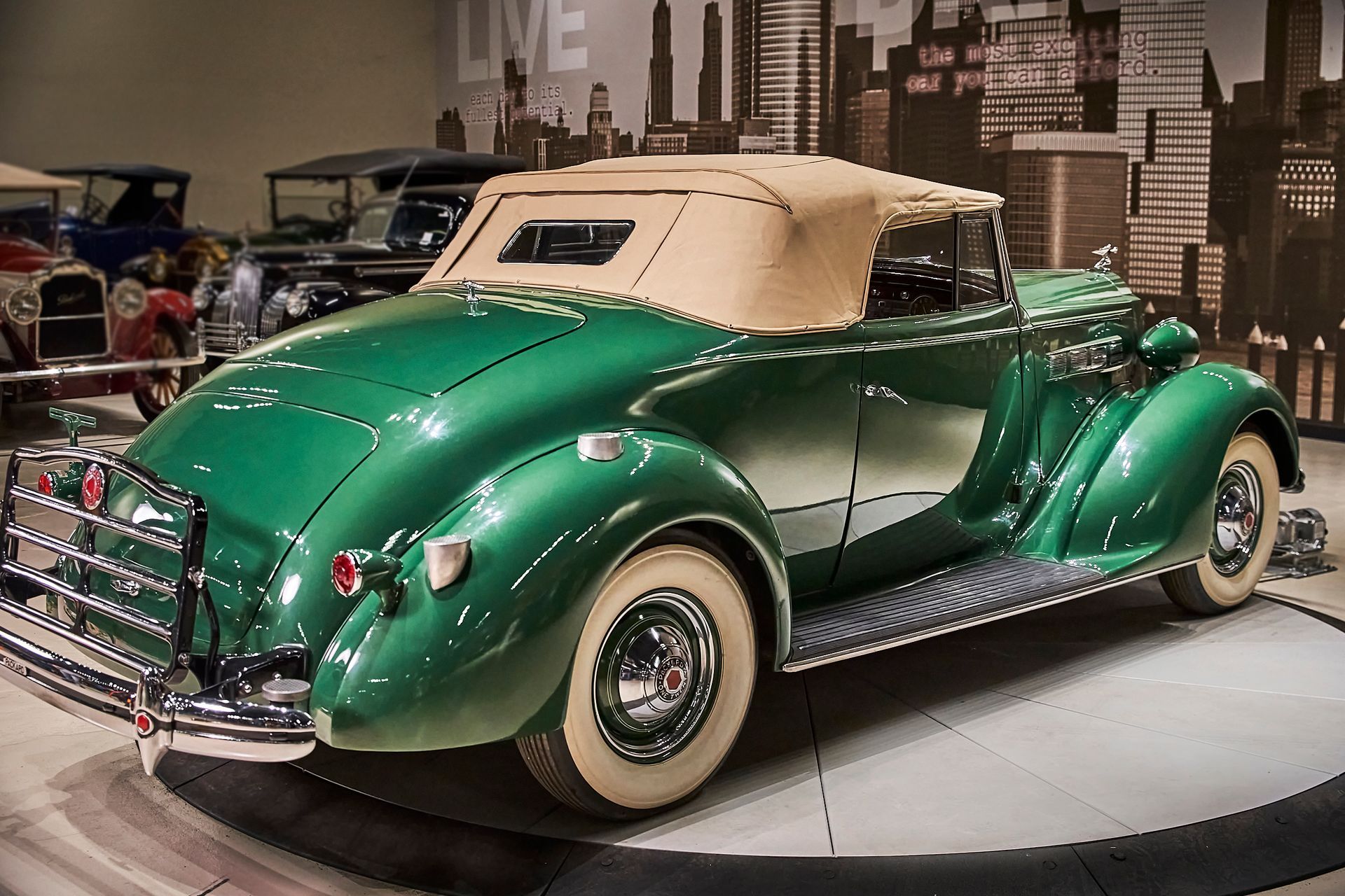 A green car with a tan top is on display in a museum