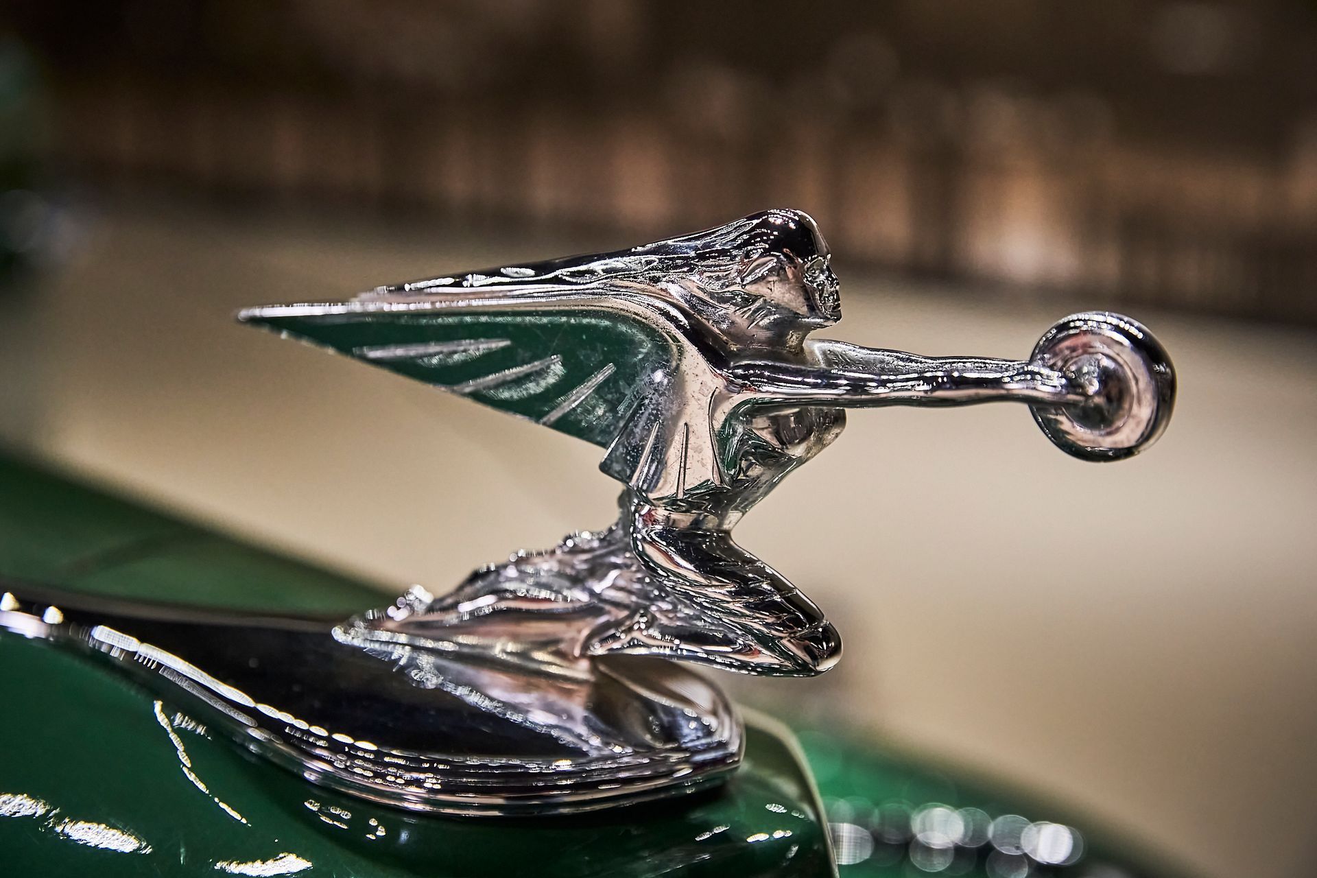 A close up of a car hood ornament on a green car.