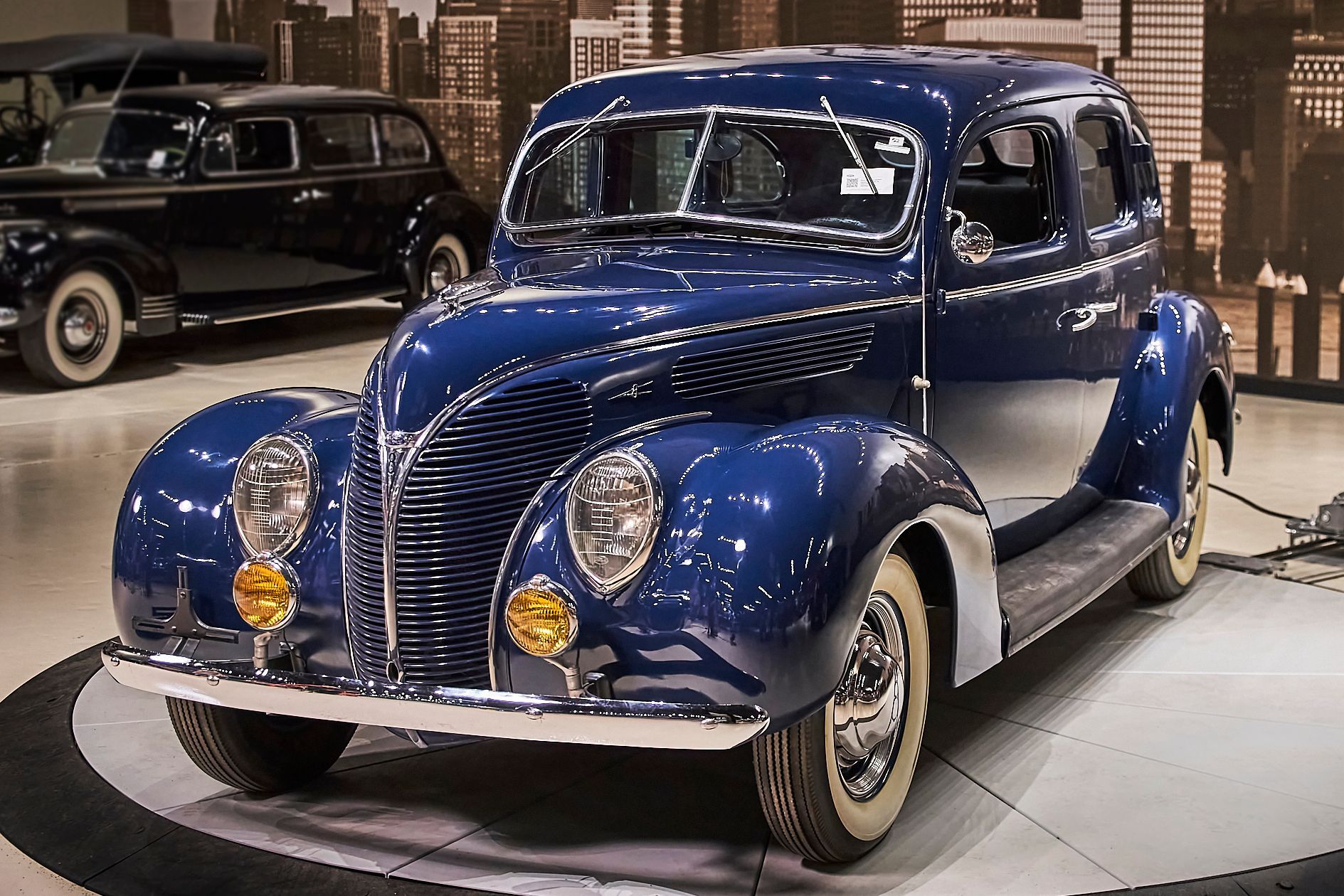 A blue vintage car is parked in a showroom