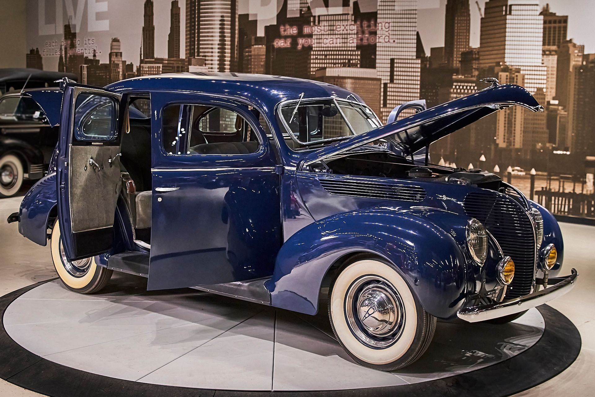 A blue car with the hood up and the doors open