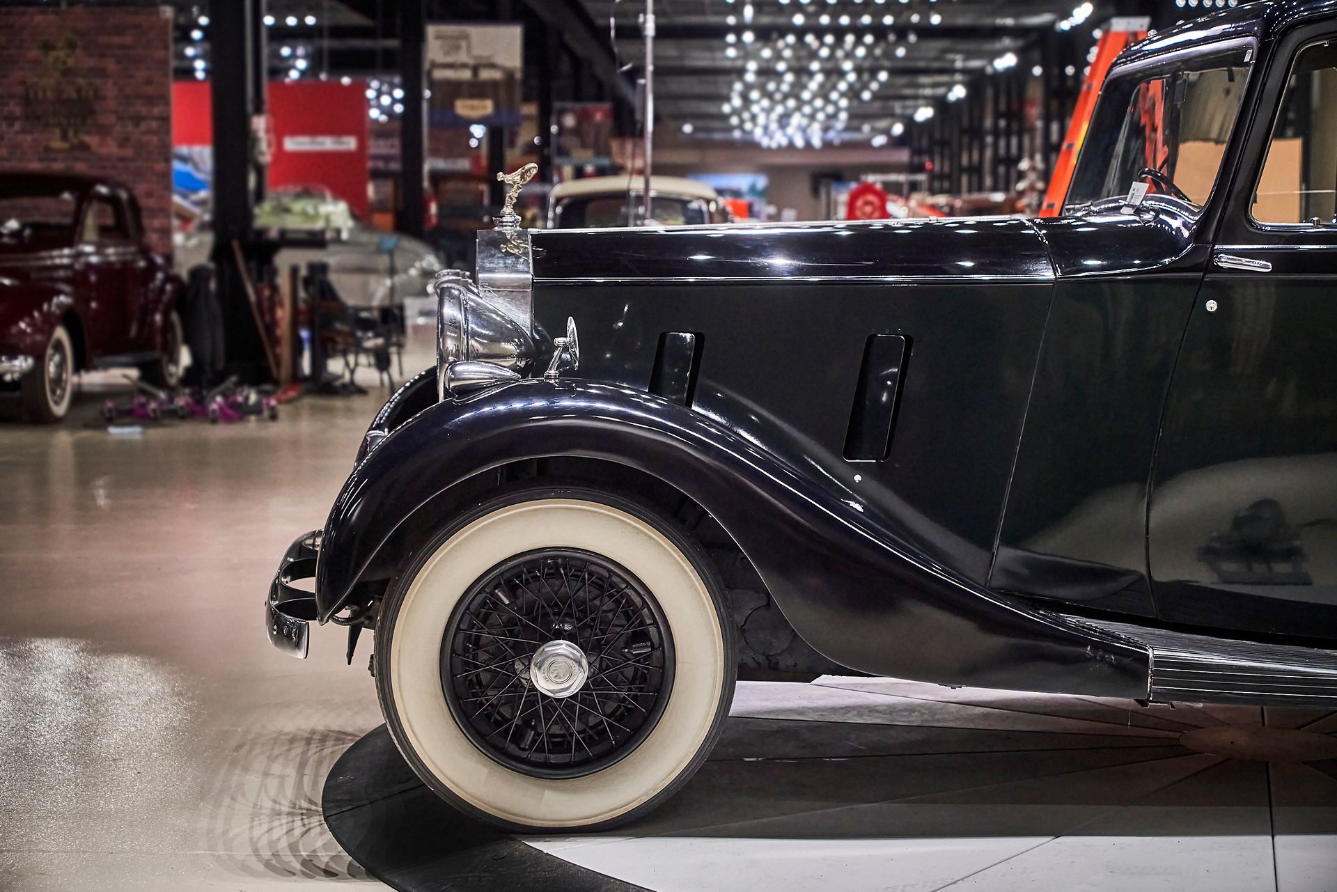 A black car with white tires is parked in a garage