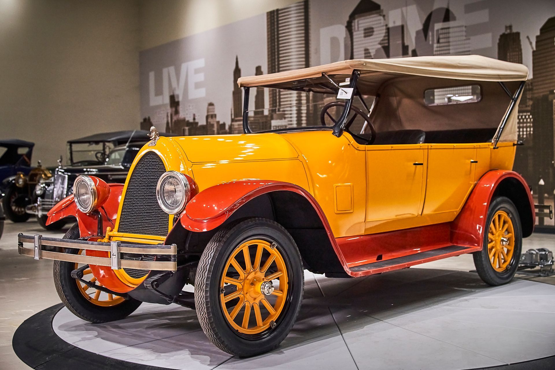 An old yellow and red car is parked in a garage.