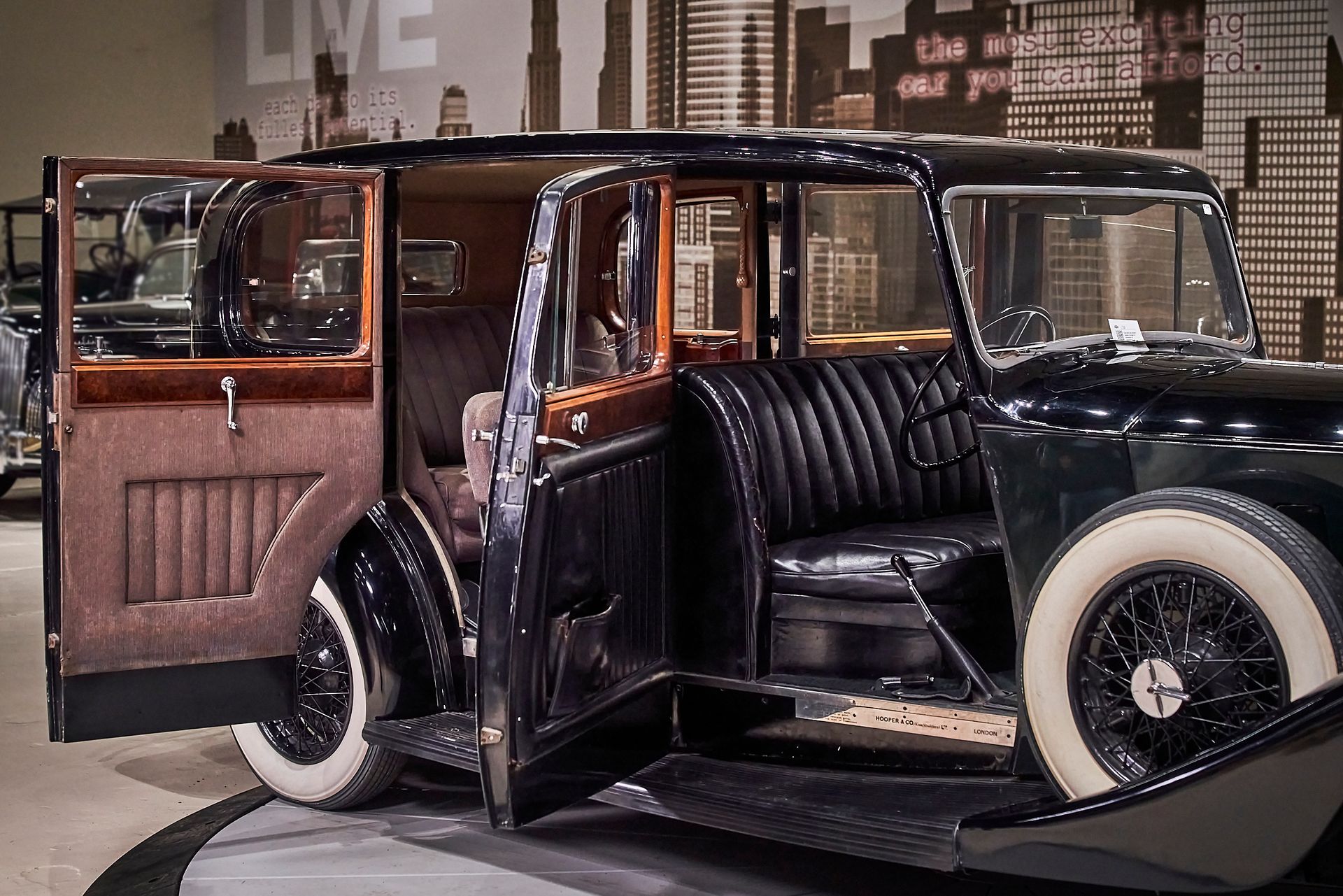 A black car with the doors open and the word live in the background