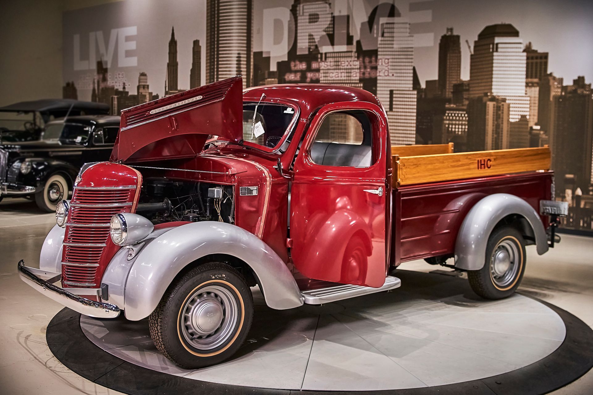 A red truck with the hood open is parked in front of a wall that says live and drive